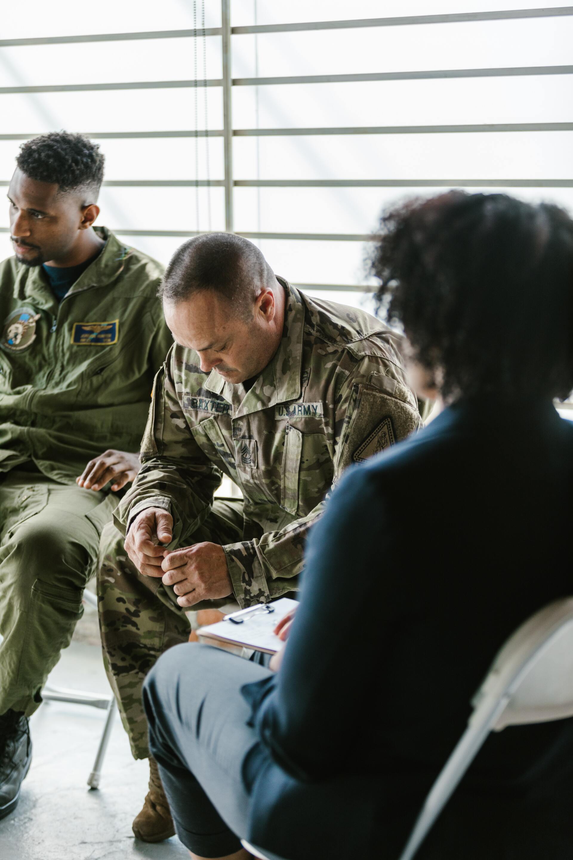 Three people in a circle, one in military uniform. They appear to be in a therapy session.