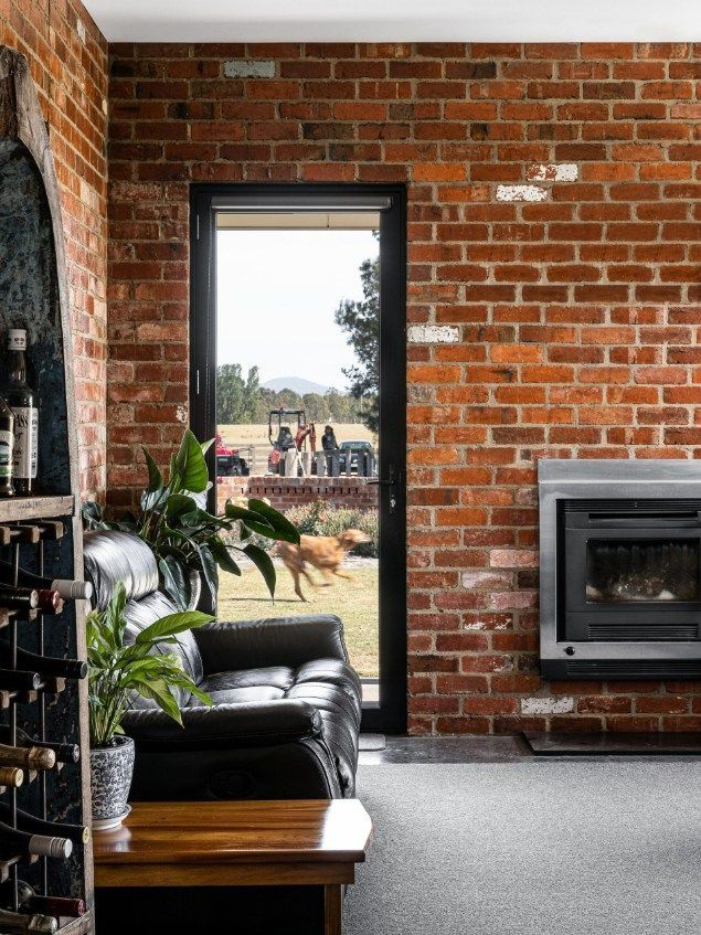 A Room With Exposed Brick Walls, a Leather Couch, and a Black-framed Door — Architectural Glass Solutions QLD in Cooroy, QLD