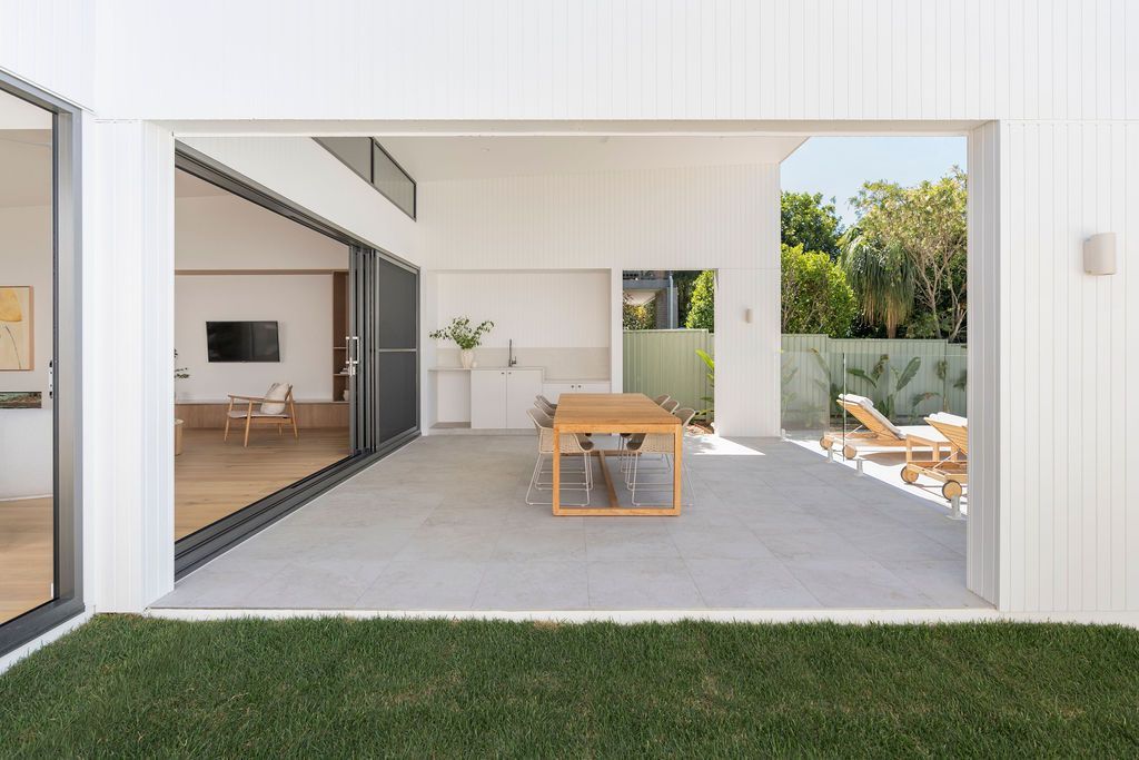 Exterior view of a white house with a sliding glass door open to an outdoor patio — Architectural Glass Solutions QLD in Cooroy, QLD
