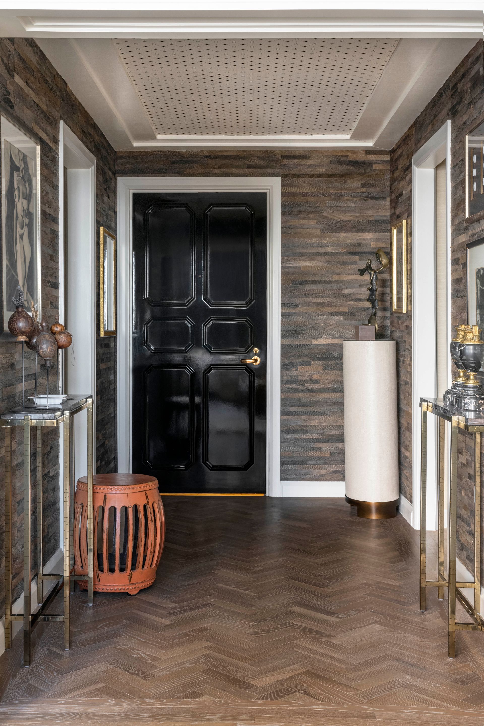 A hallway with a black door and a wooden floor.