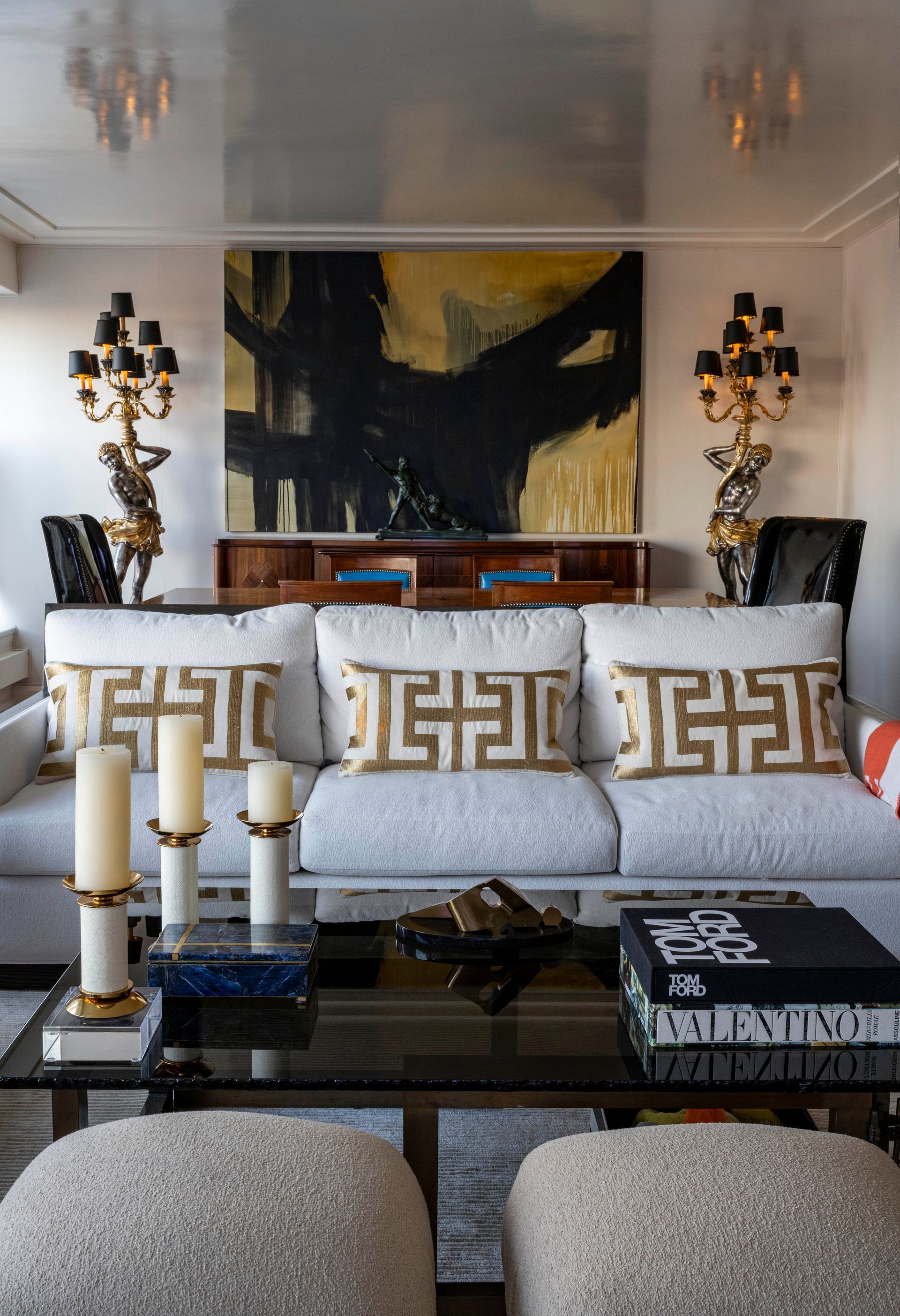 A living room with a couch , coffee table , candles and a painting on the wall.