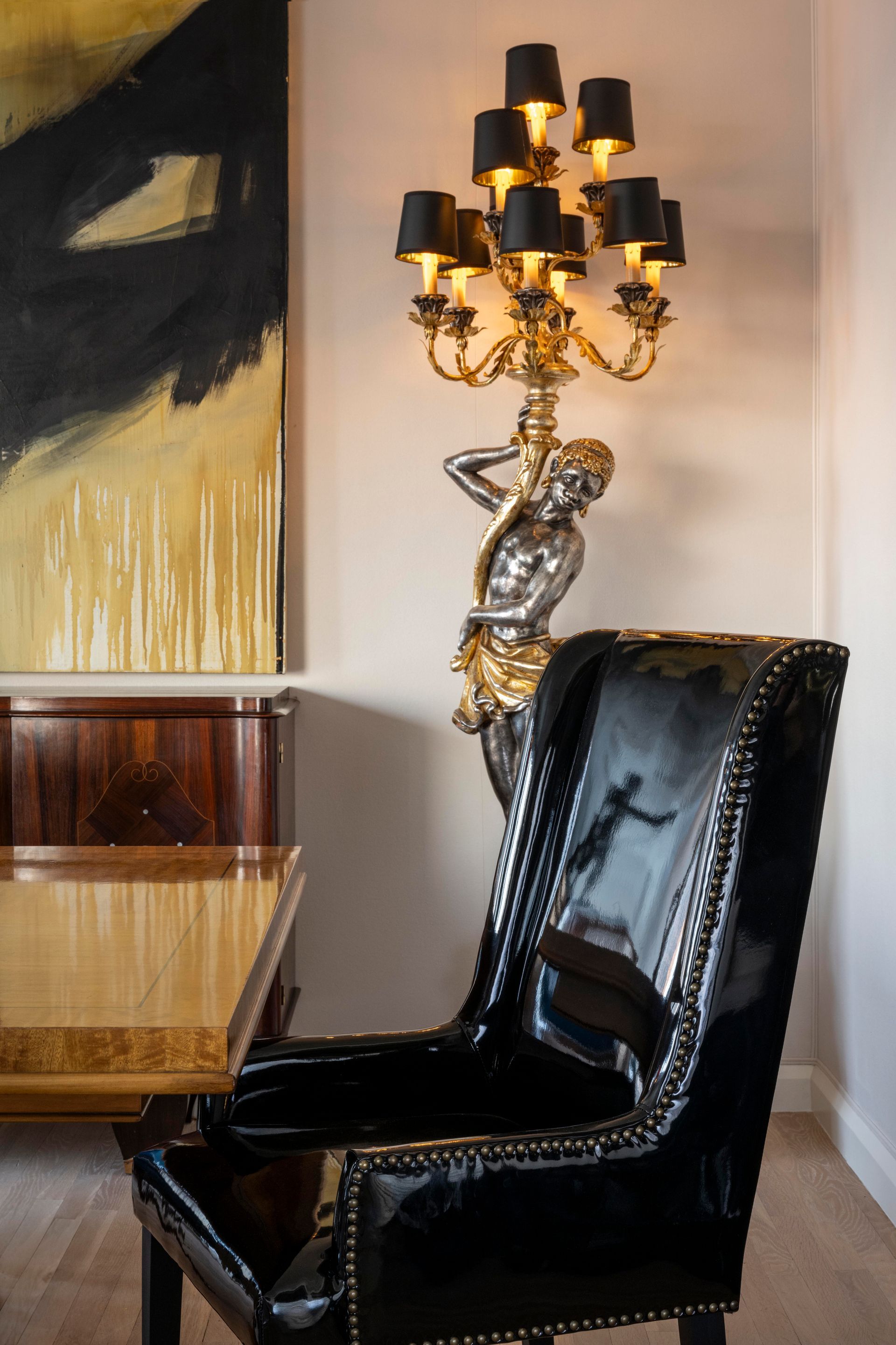 A dining room with a table and chairs and a lamp on the wall.
