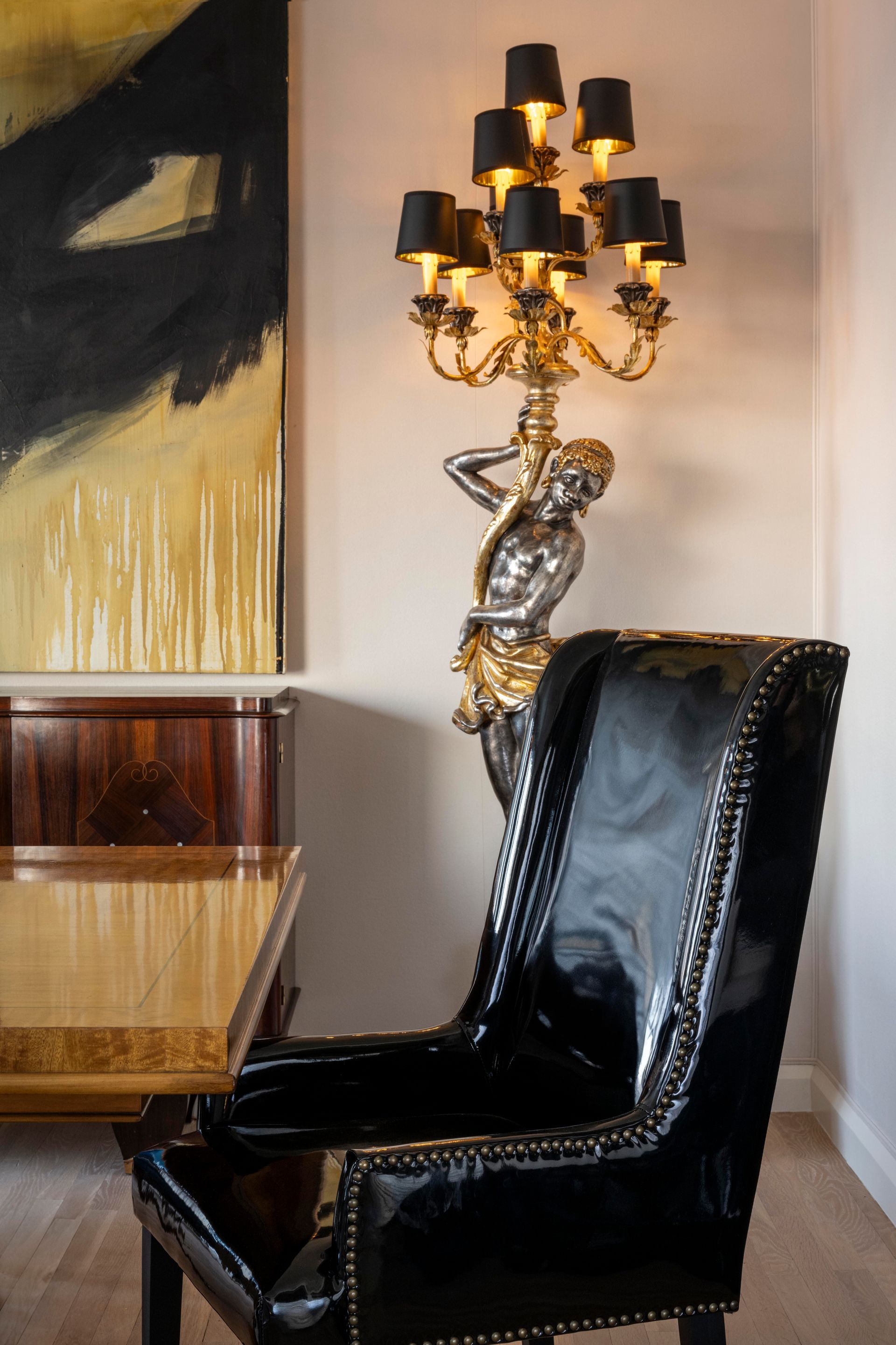 A dining room with a table and chairs and a lamp on the wall.