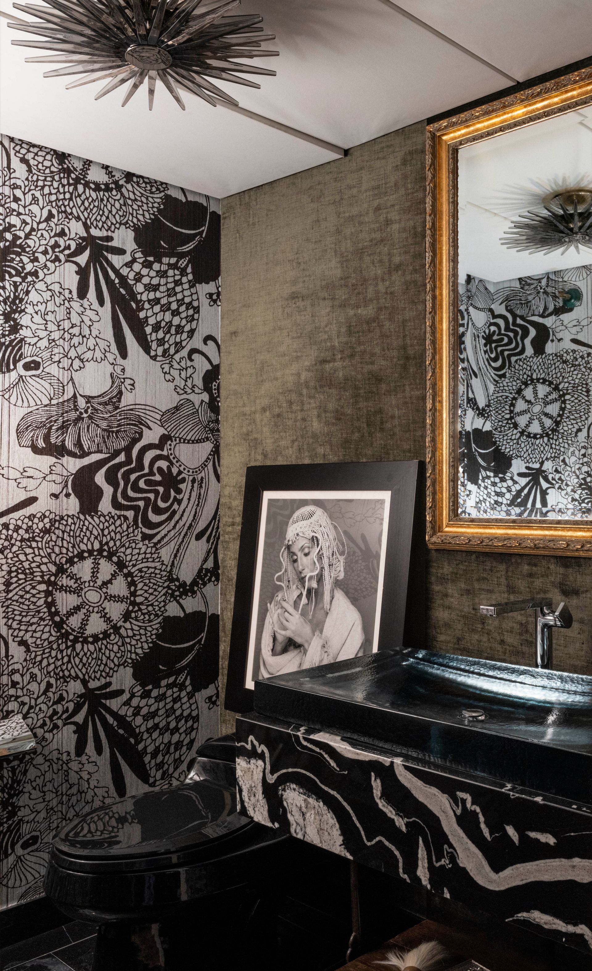 A bathroom with a toilet , sink , mirror and picture on the wall.