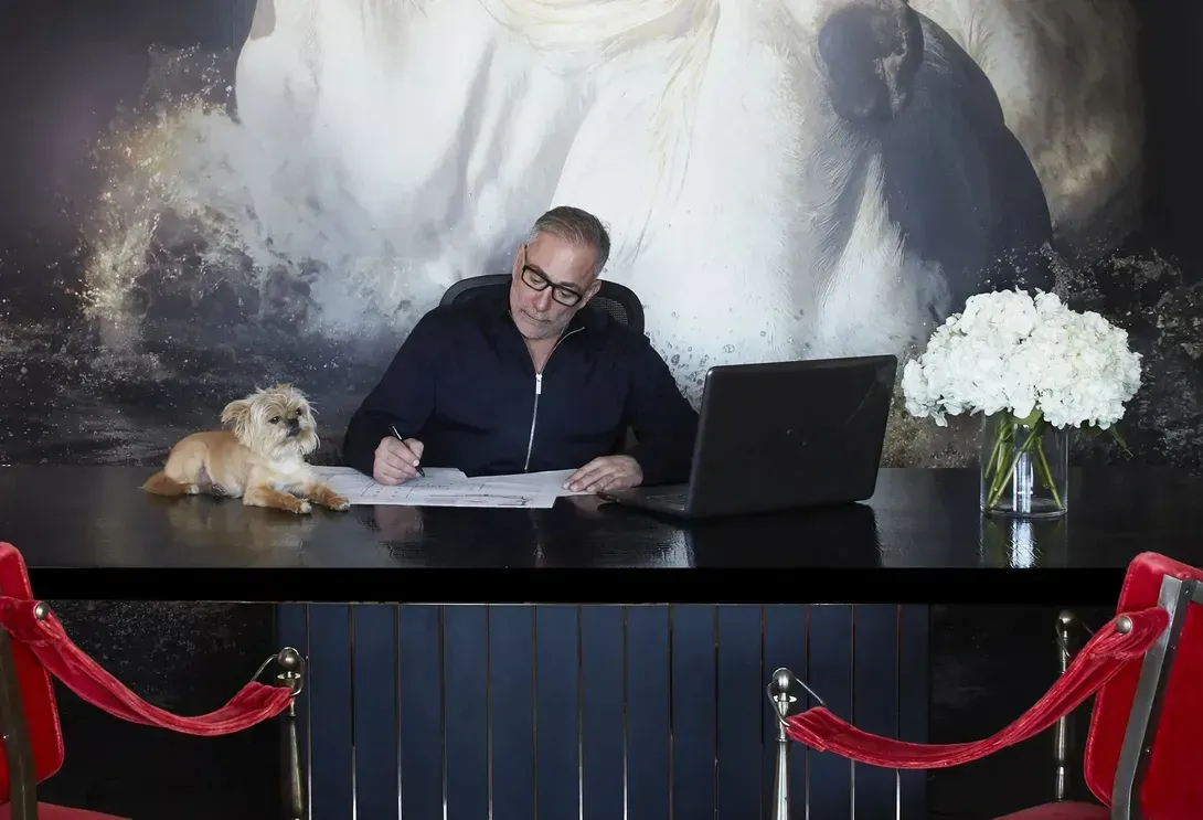 A man is sitting on a table in a room with lots of chandeliers