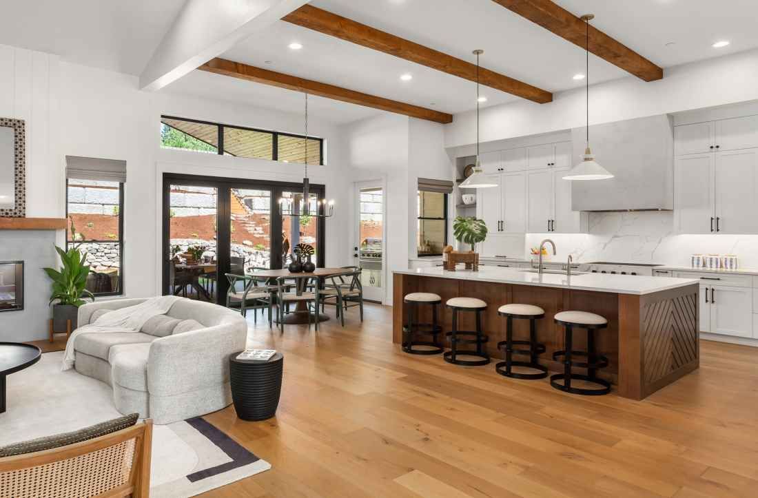A living room and kitchen in a house with hardwood floors and white cabinets.