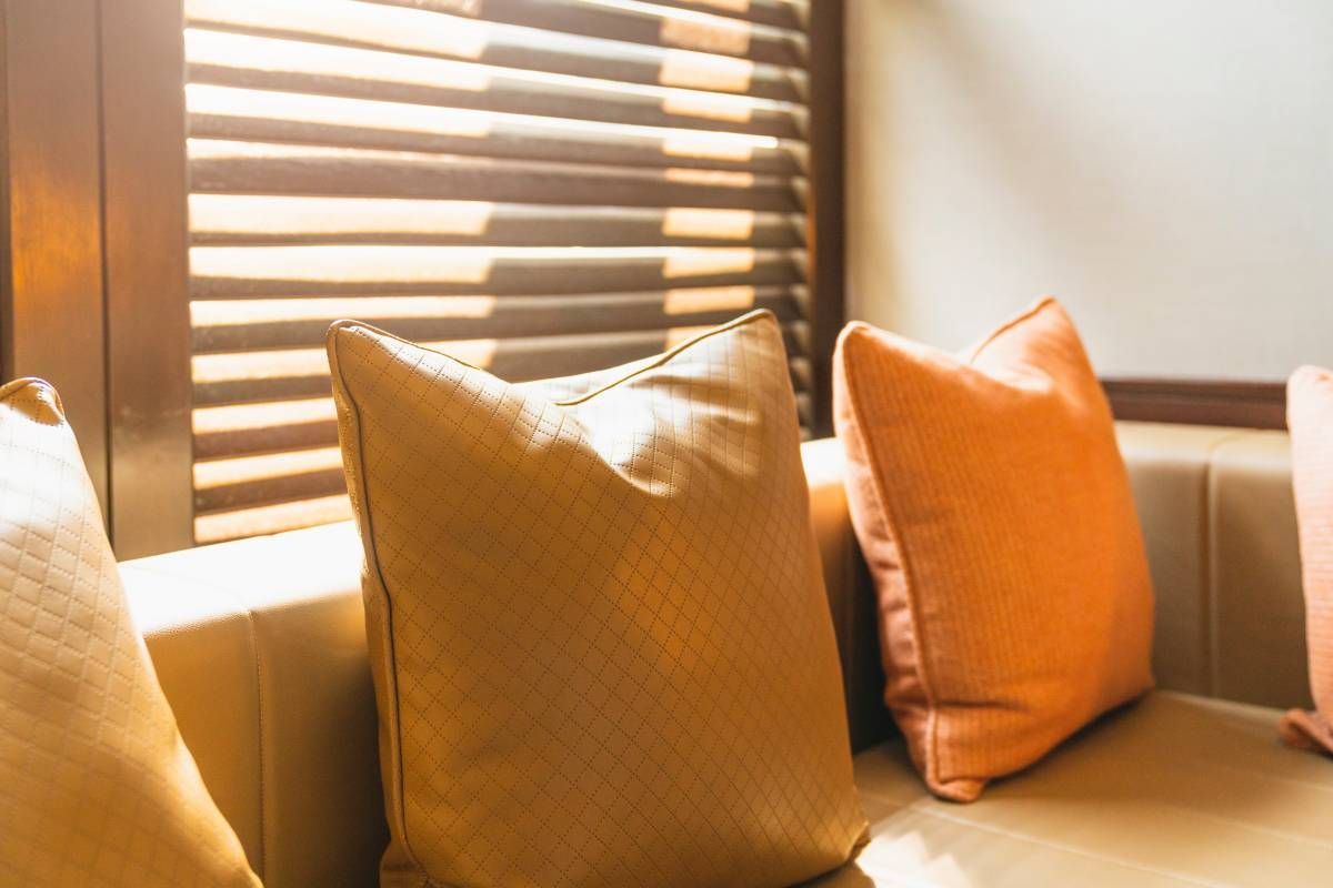 Image of a sunroom with shutters that are custom-made, cozy window seating, and throw pillows near Tustin, CA
