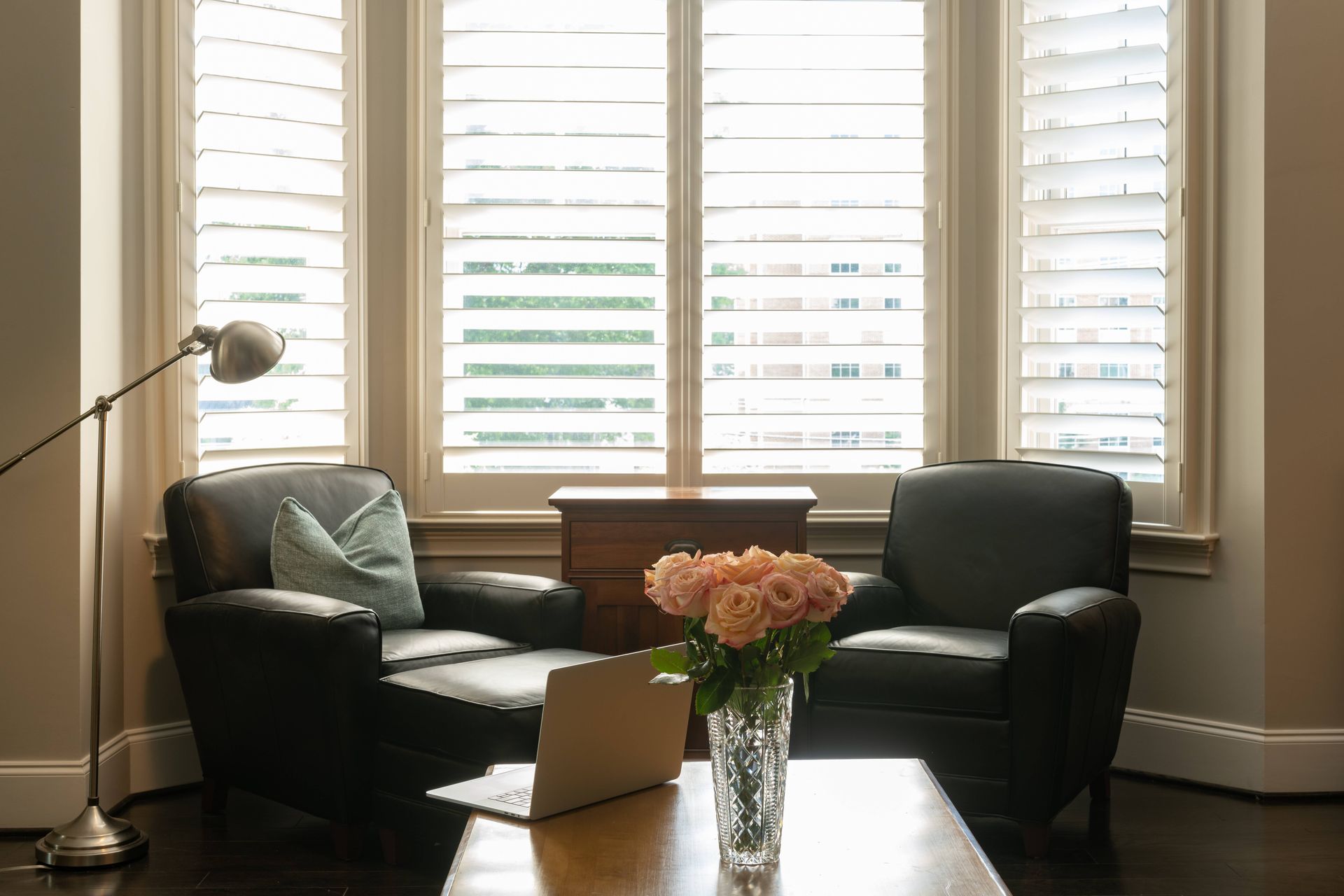 Custom shutters on bay windows in a cozy nook of a home office, featuring two armchairs at Custom Wo