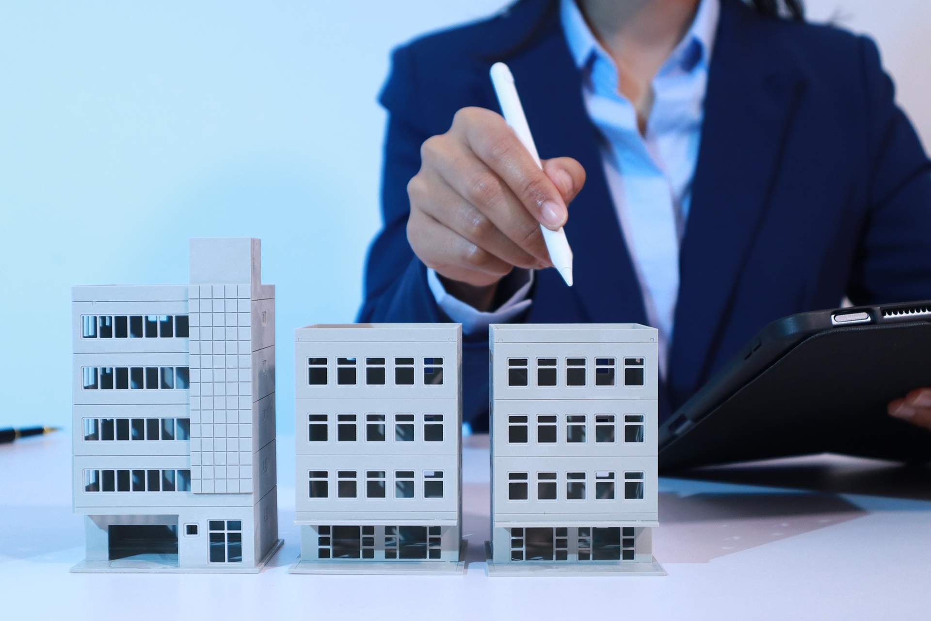 Businessperson pointing at model office buildings with a pen during a property meeting
