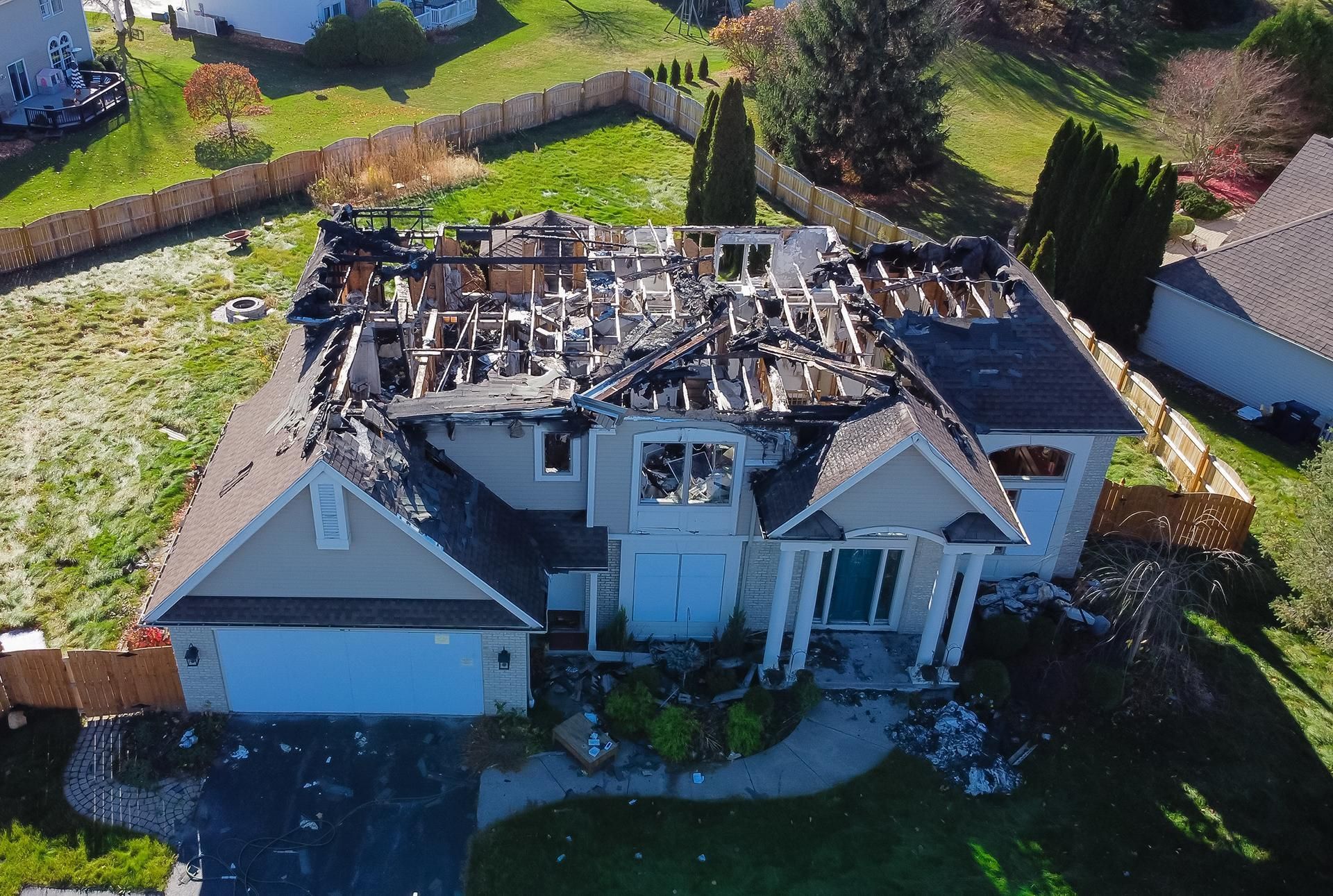 Aerial view of a house with severe roof fire damage and debris around it