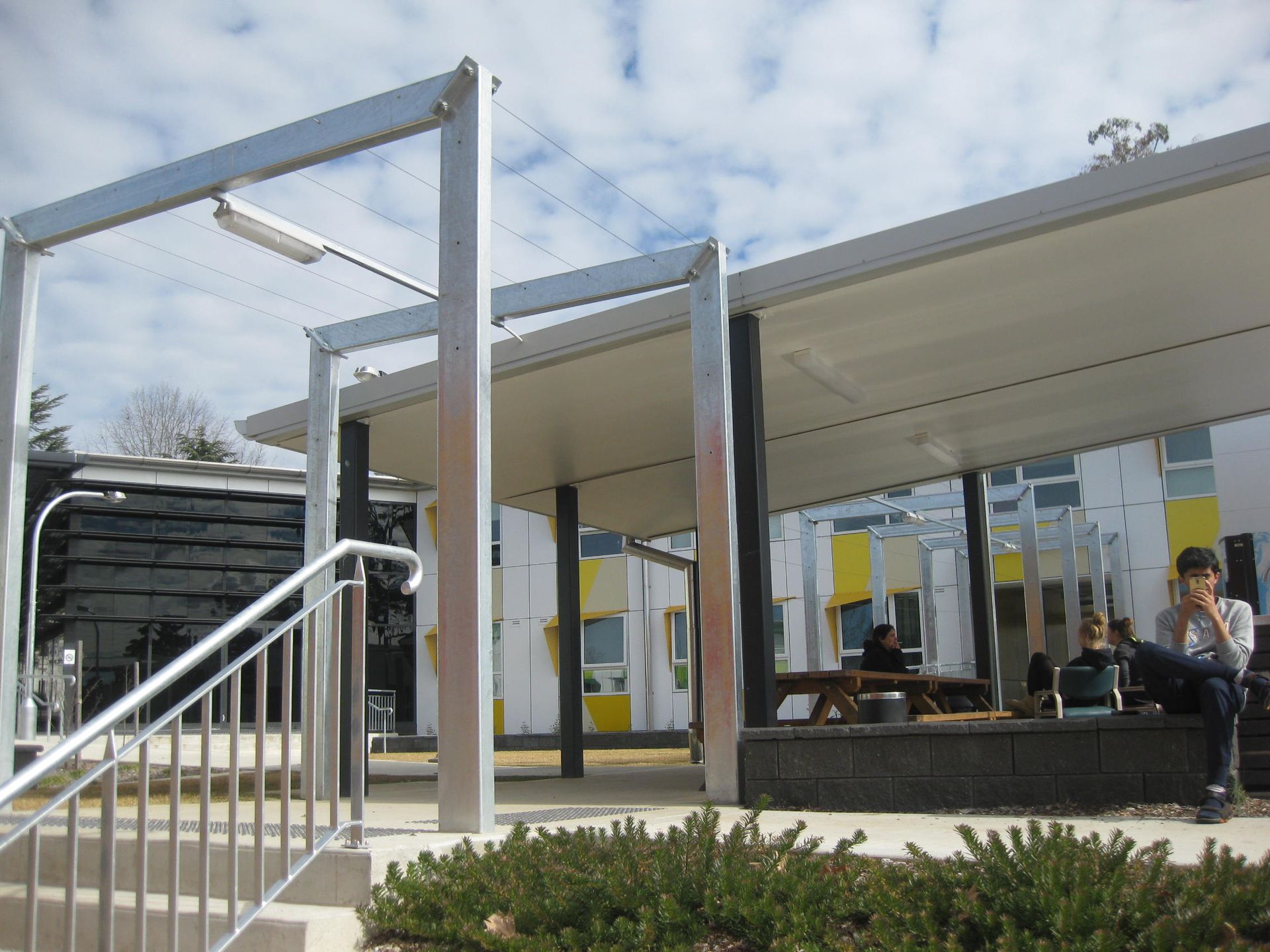 people sitting under pergola at wright college with painted yellow and green stripes in the background