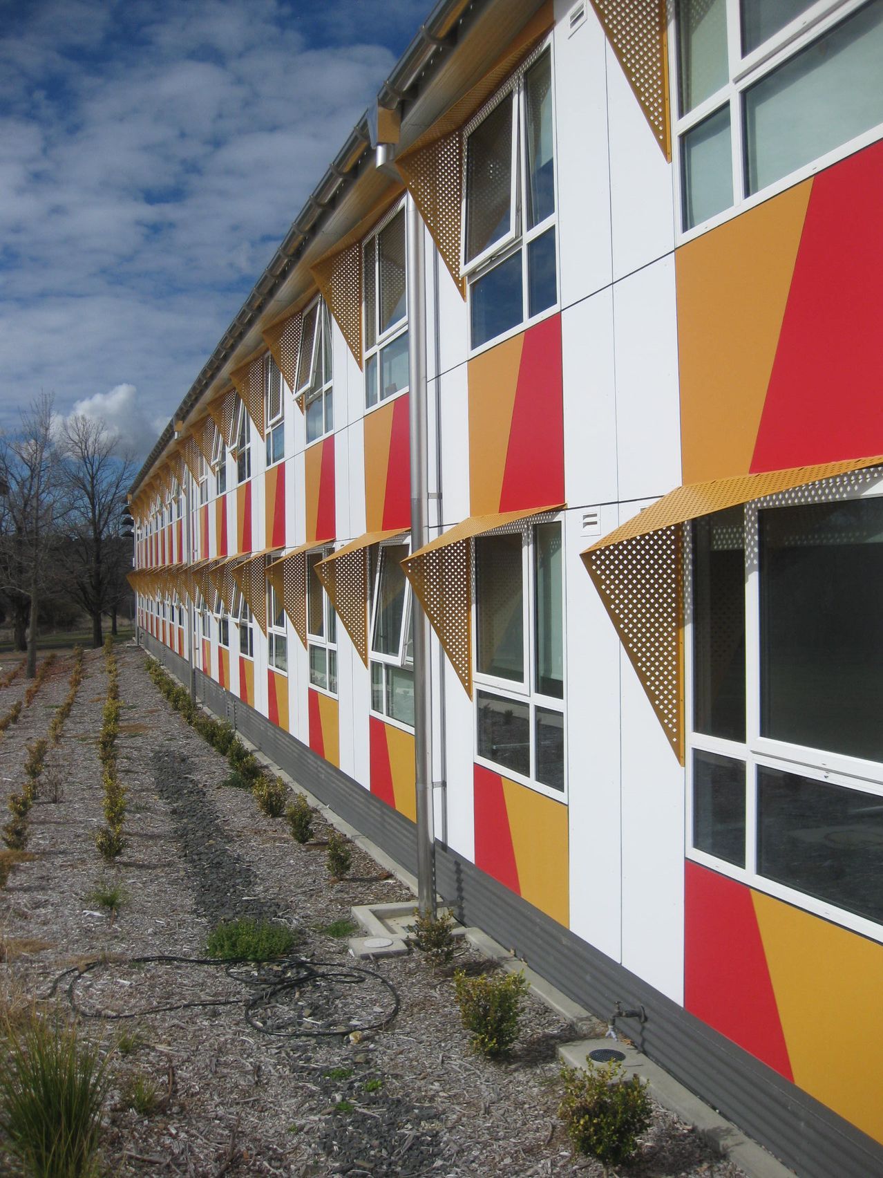 Exterior painted wall with orange red and white pattern at wright college armidale. Painted by love paint