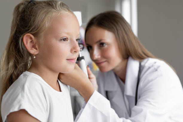 A doctor is examining a little girl 's ear with a otoscope