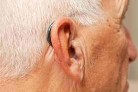 A person is holding a hearing aid in their hands.
