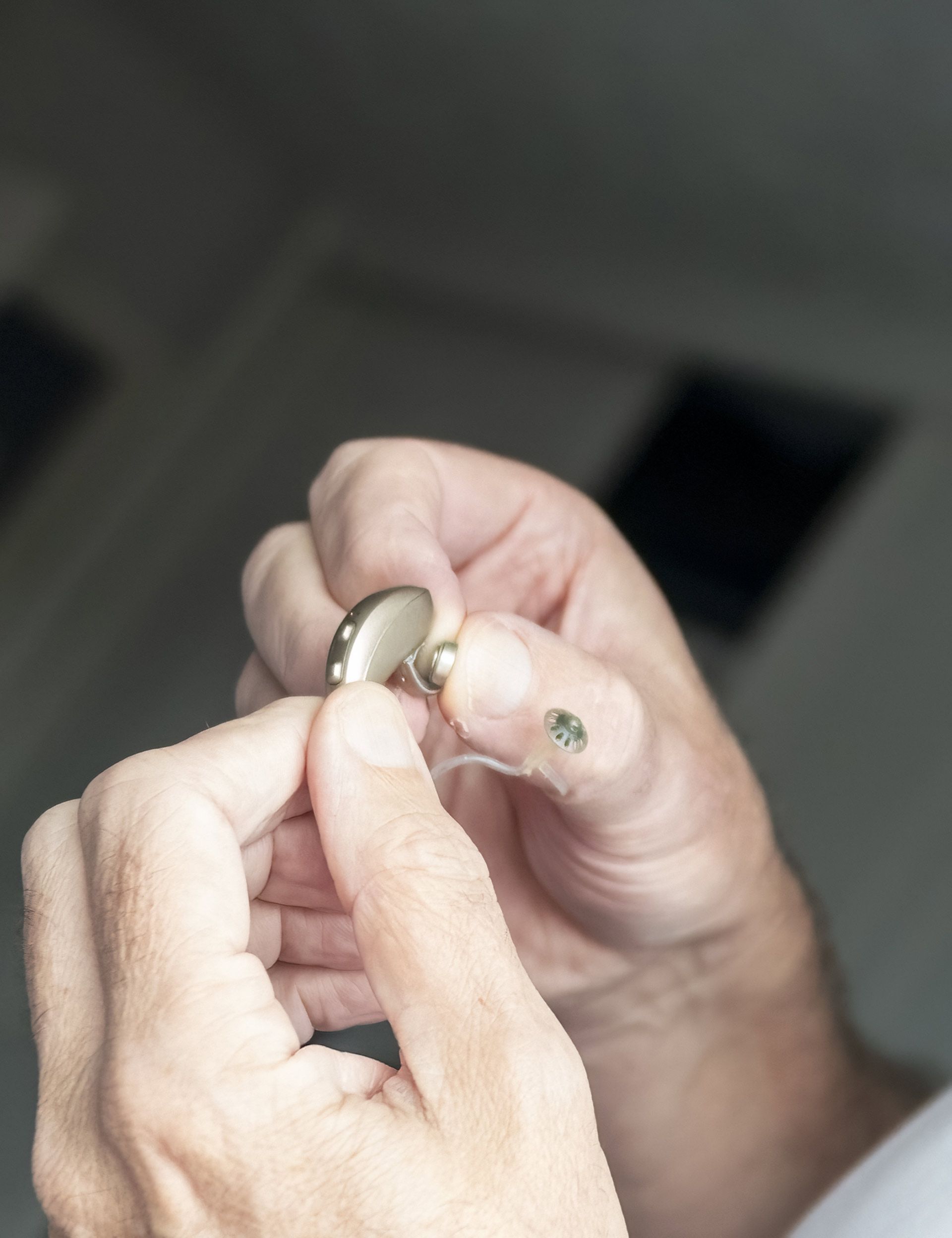 A person is holding a hearing aid in their hands