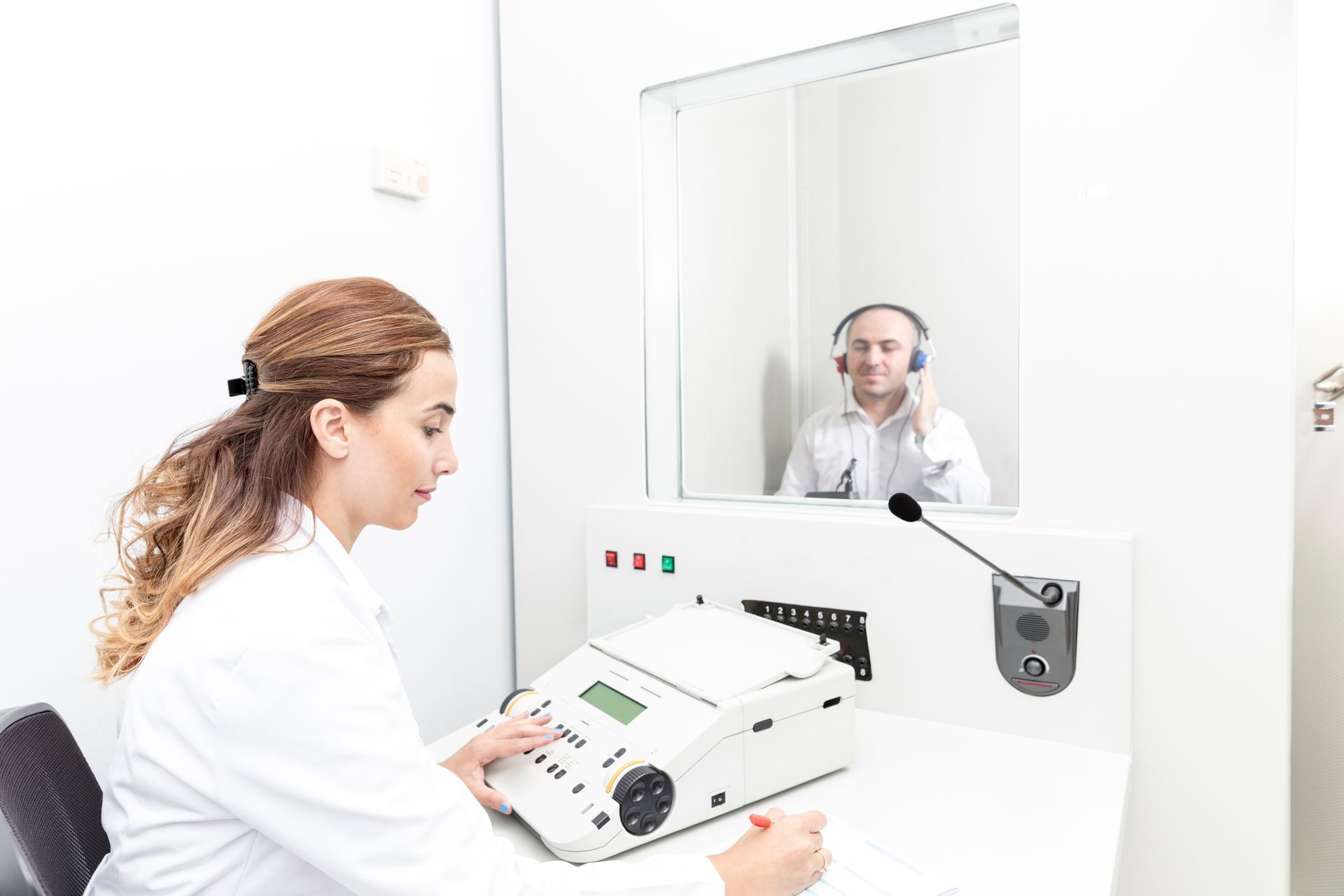 A doctor is examining an older man 's ear with a hearing aid