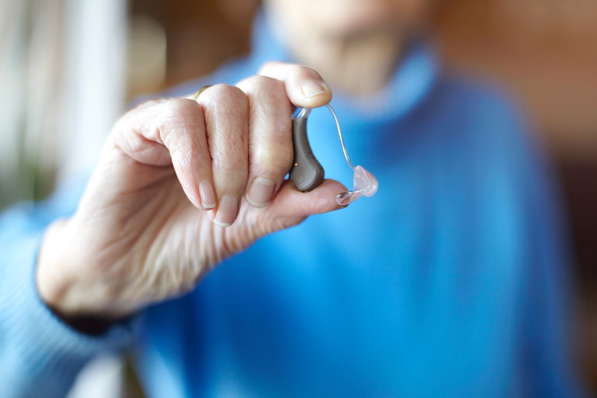A woman is putting a hearing aid in her ear