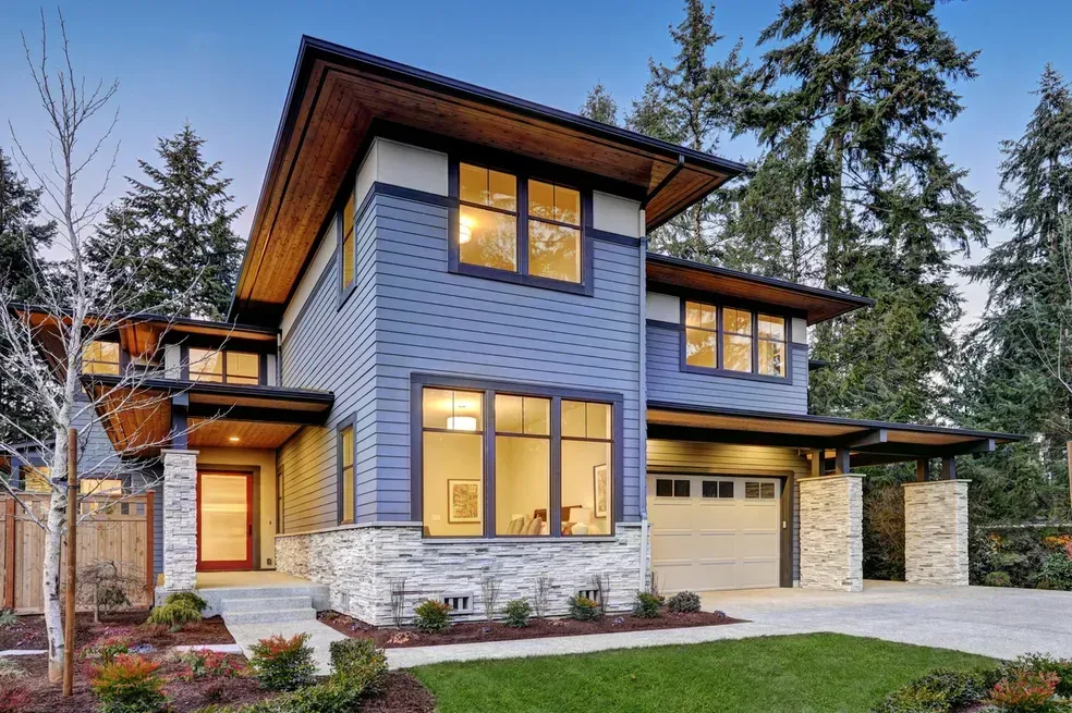 A blue and white house with a lot of windows is surrounded by trees.