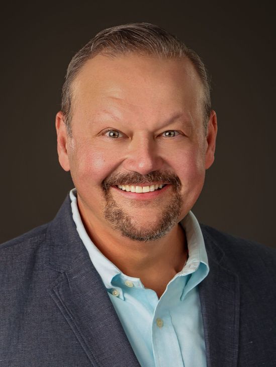 A man with a beard and a blue jacket is smiling for the camera.