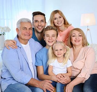 Family of six smiling on a couch in a bright living room