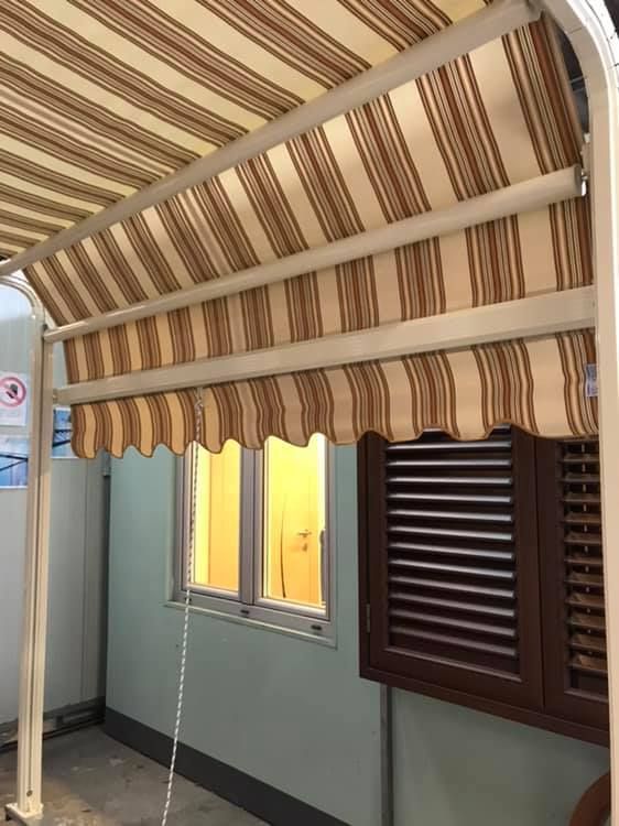 Una tenda a strisce marroni e bianche è appesa sopra una finestra.