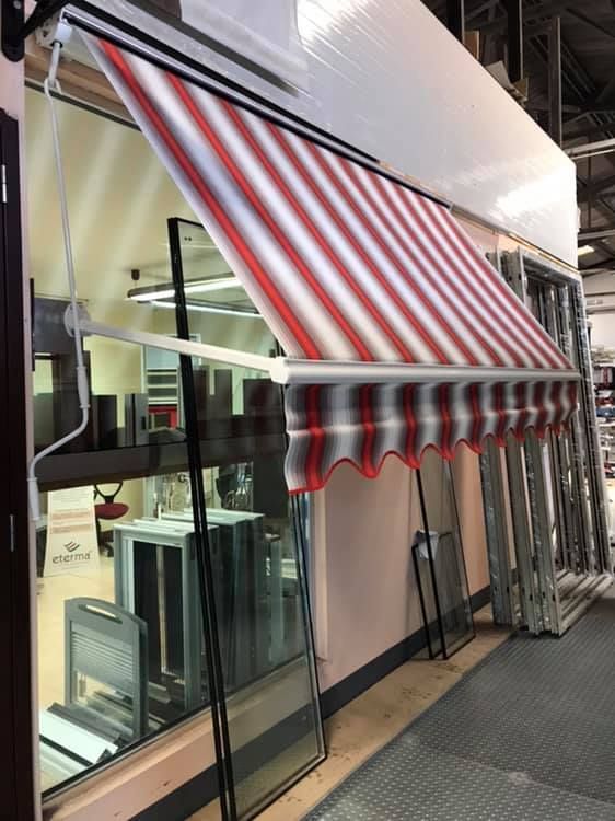 Una tenda a strisce rosse e bianche è appesa al lato di un edificio