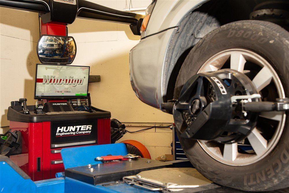 Car wheel on a Hunter tire balancing machine in a garage, with tools nearby.