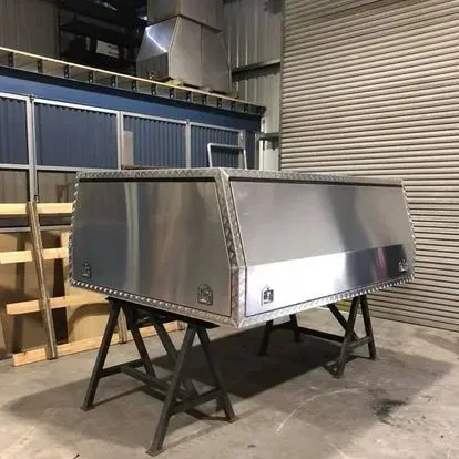Large silver metal equipment housing on black stands, in an industrial warehouse.