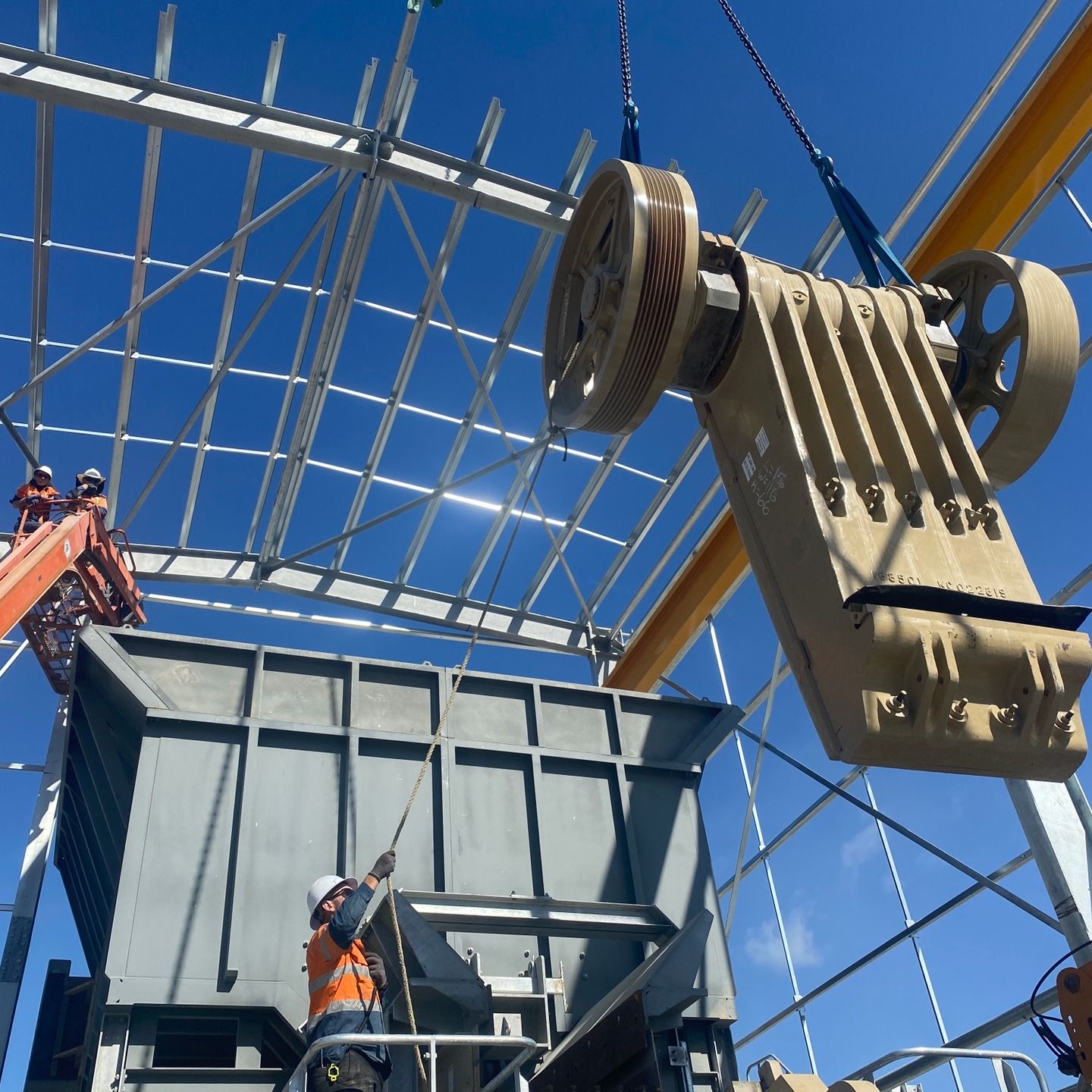 Construction workers lifting a large steel panel with a crane at an unfinished building site