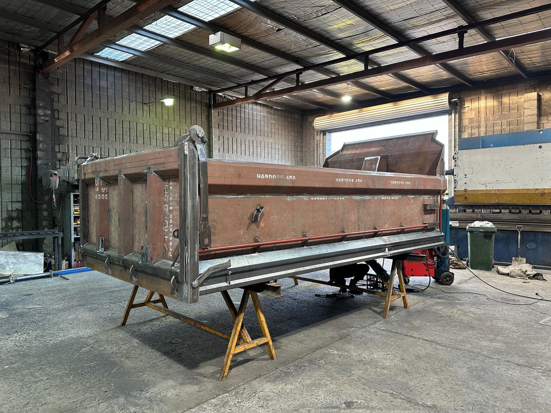 Rusty brown truck bed on jack stands inside a warehouse workshop