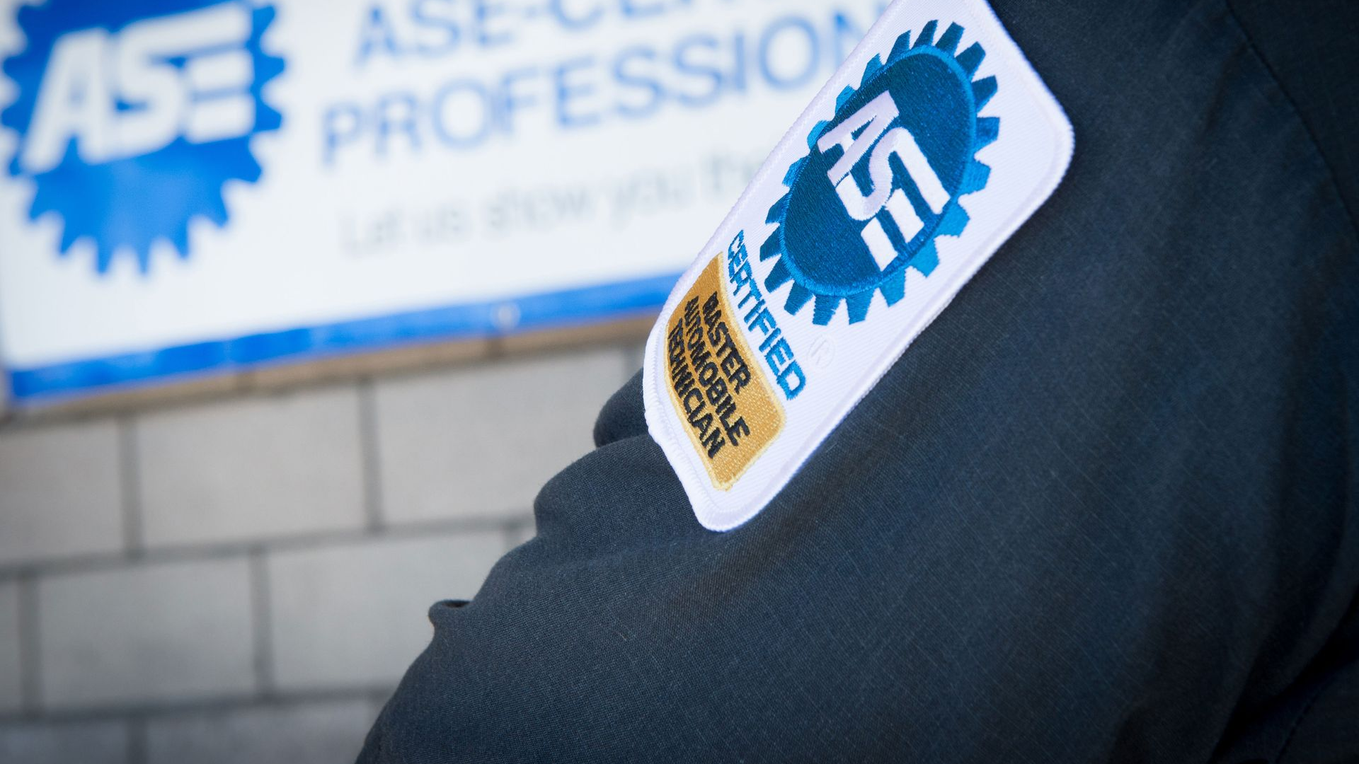 ASE-certified mechanic sleeve patch in front of an ASE professional sign