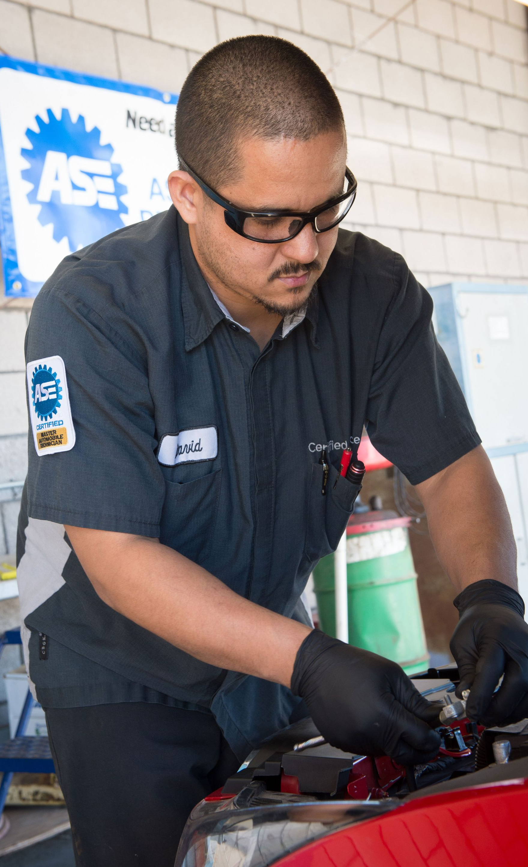Mechanic in dark uniform and gloves working on a car engine in a garage