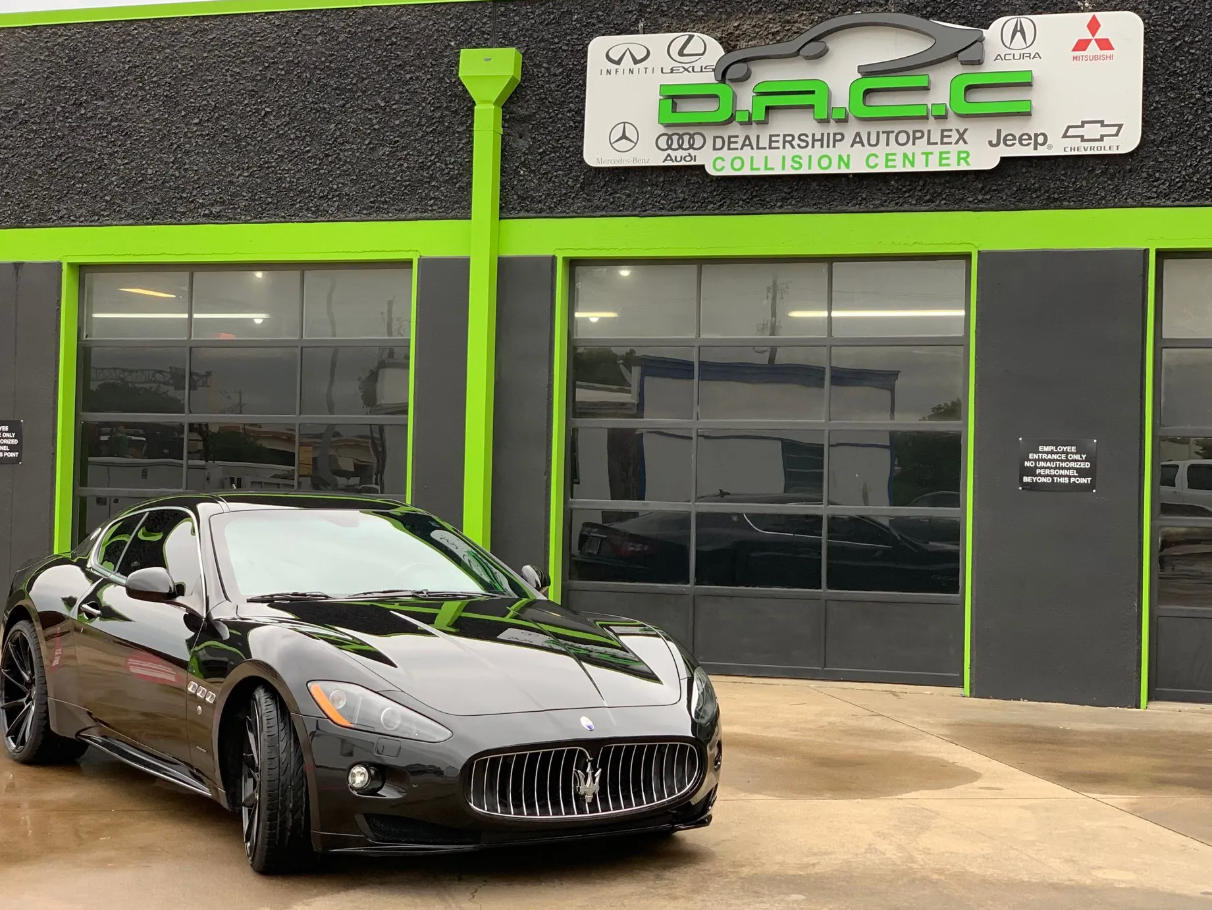 Black Maserati sports car parked in front of a collision center with a green and black exterior.