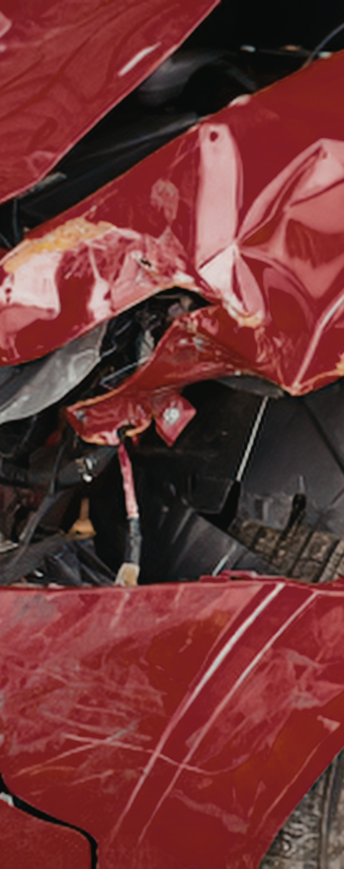 Mechanic kneeling beside a black car in a garage, inspecting the lower side panel.