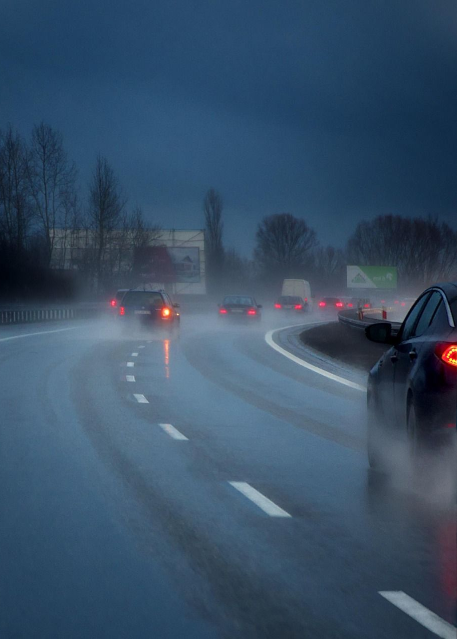 Cars driving on a wet highway during a dark, rainy day.