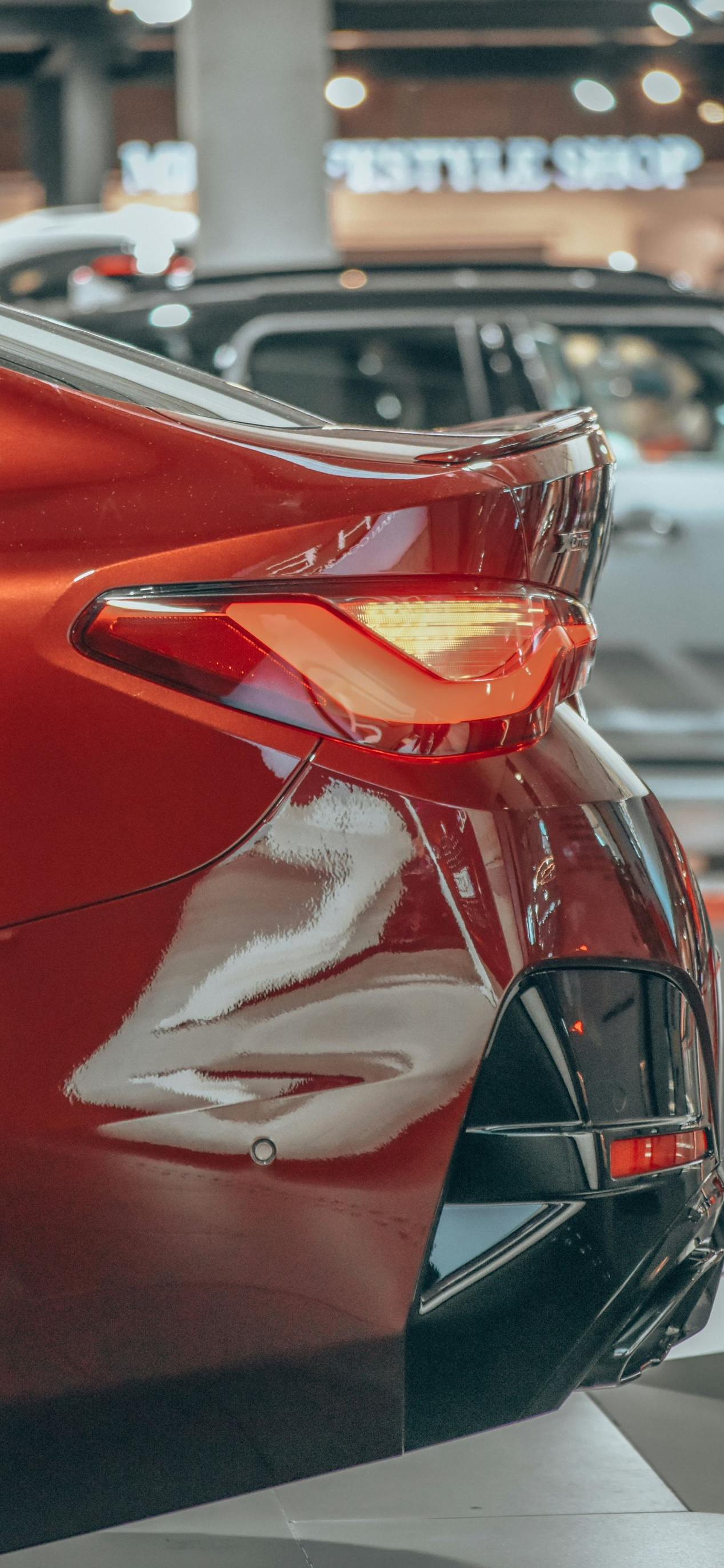 Close-up of a red car’s rear taillight and bumper at an auto show