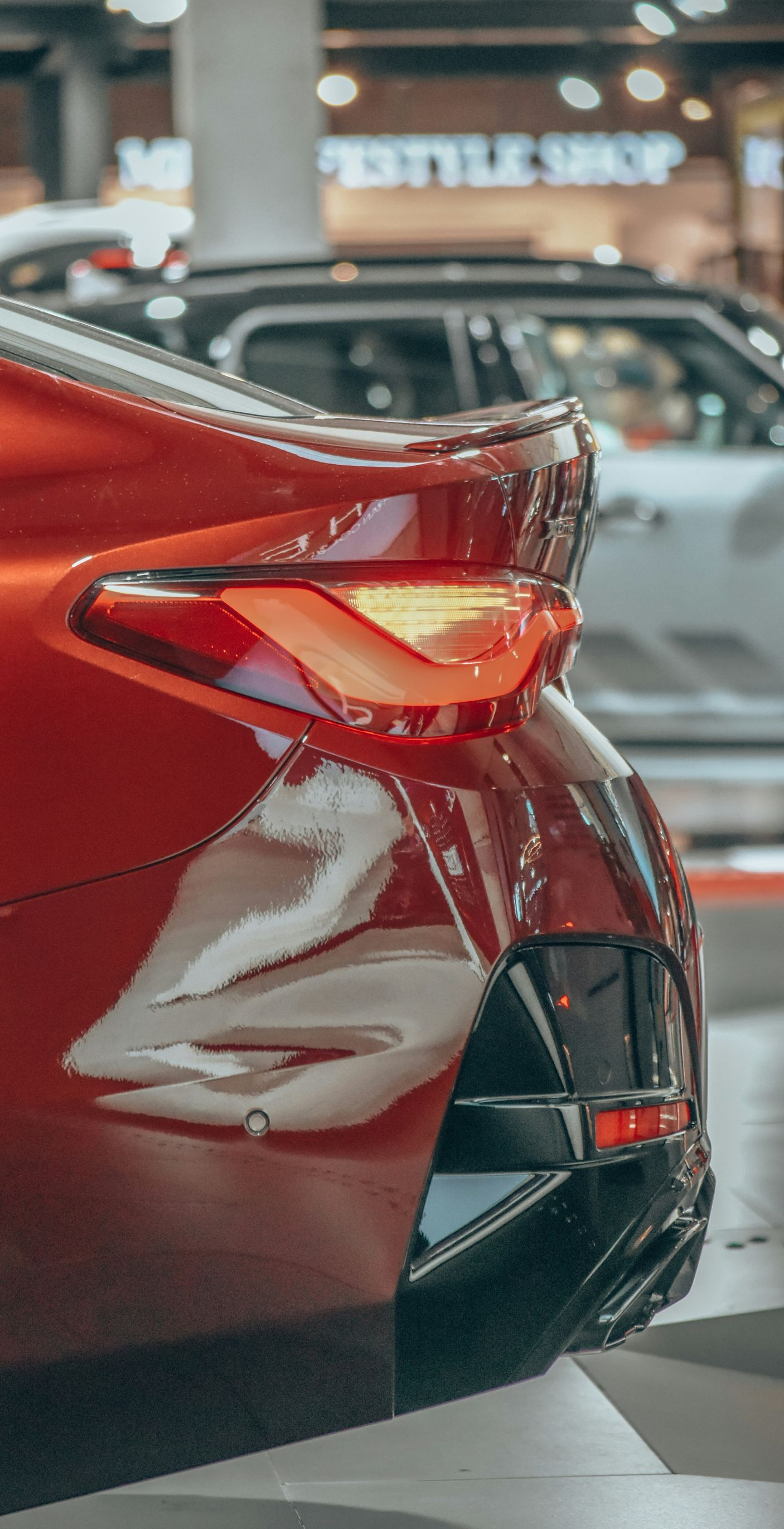 Close-up of a red car’s rear taillight and bumper at an auto show