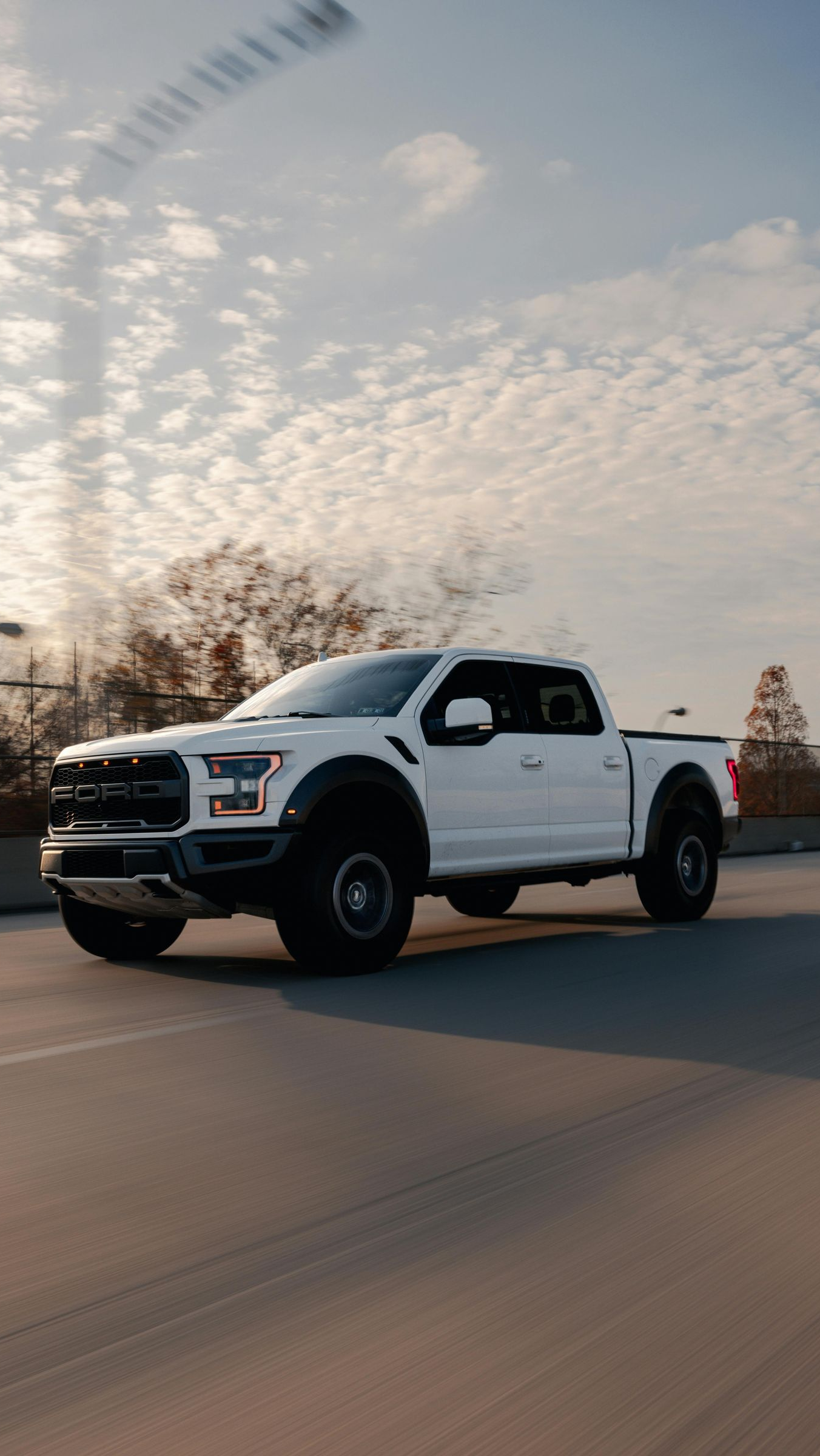 White pickup truck driving on a highway under a cloudy sky
