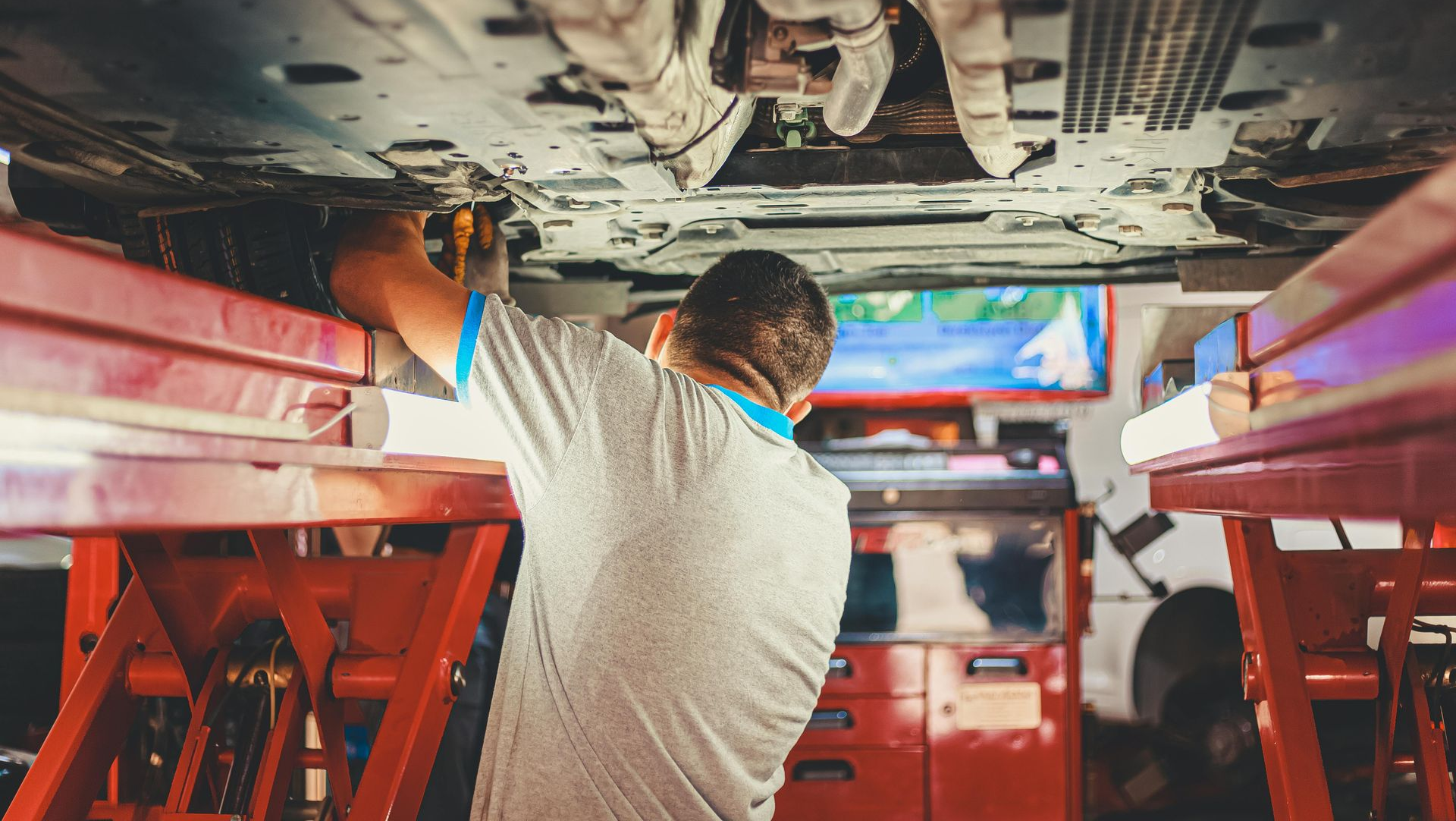 Mechanic working under a car on a lift in an auto repair shop