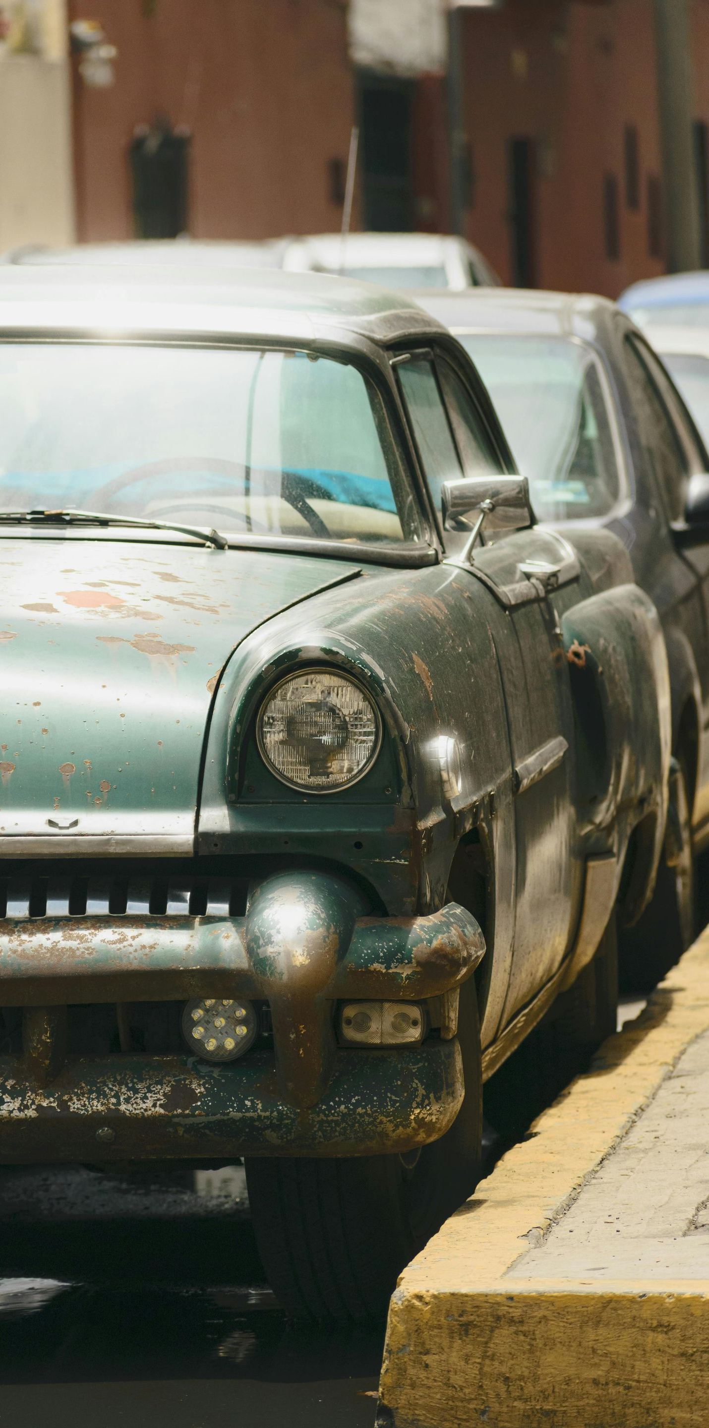 Two vintage cars parked along a curb on a city street