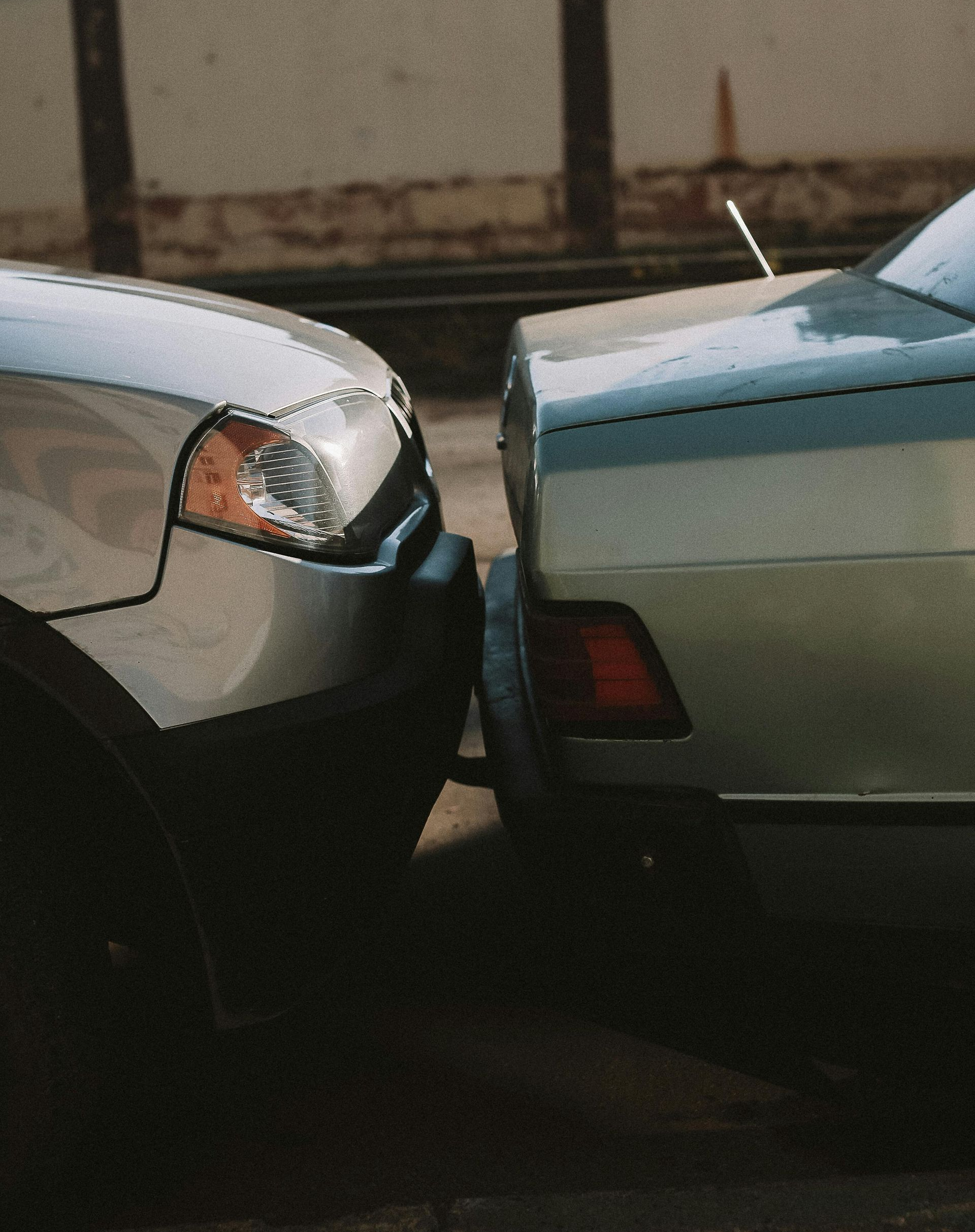 Two cars, a silver SUV and a light blue sedan, are bumper to bumper.