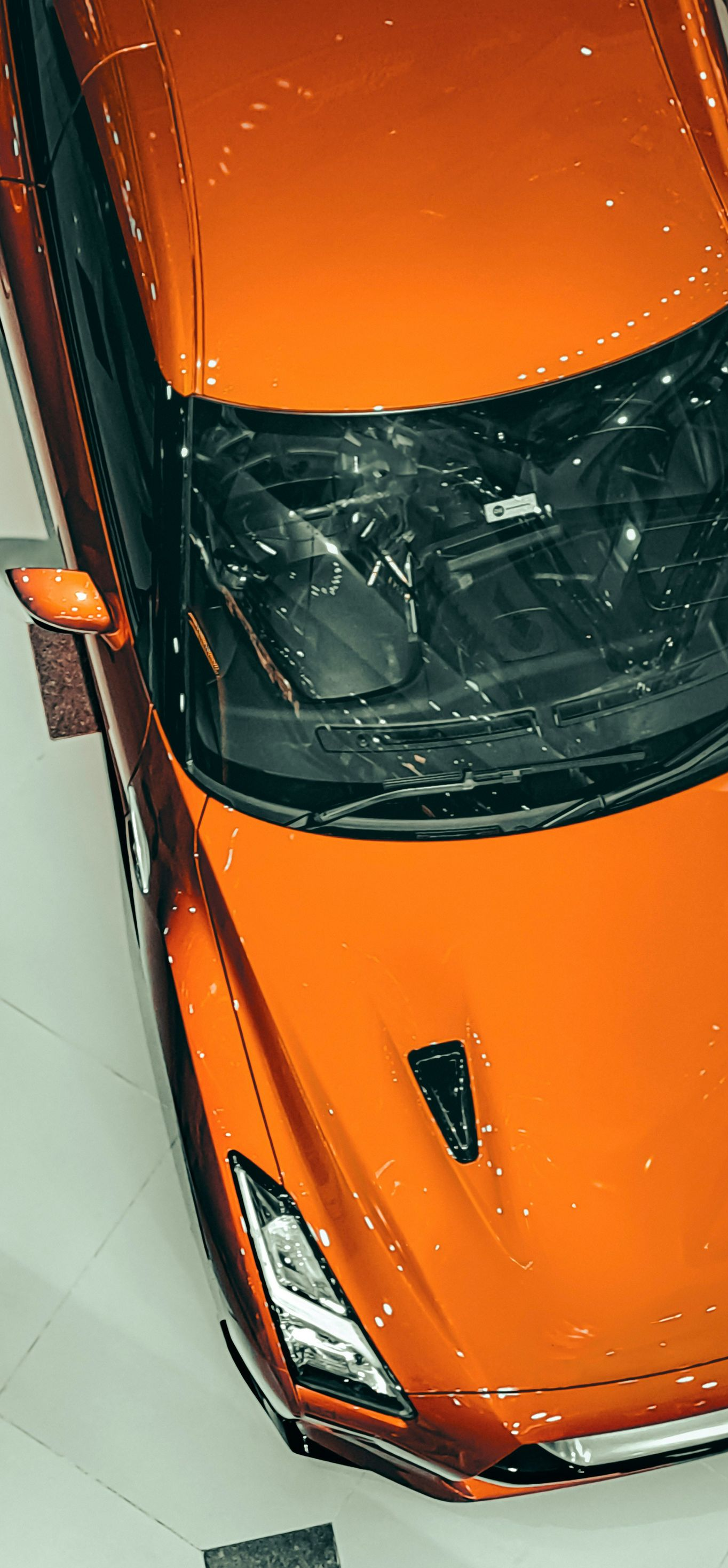 Orange sports car viewed from above in a showroom display