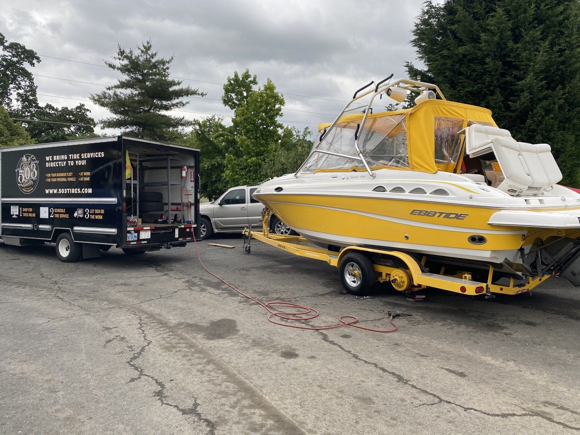 503 Tires mobile tire shop servicing a yellow motorboat on the road.