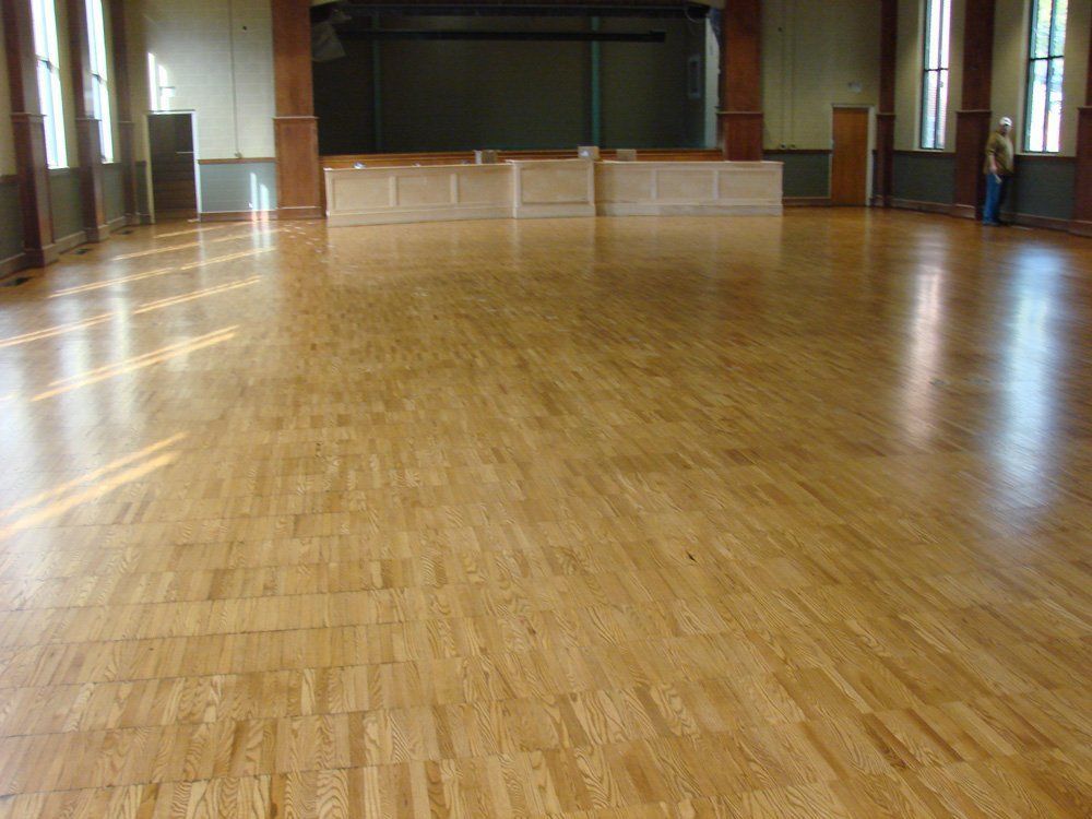 A large room with a wooden floor and a stage in the background.
