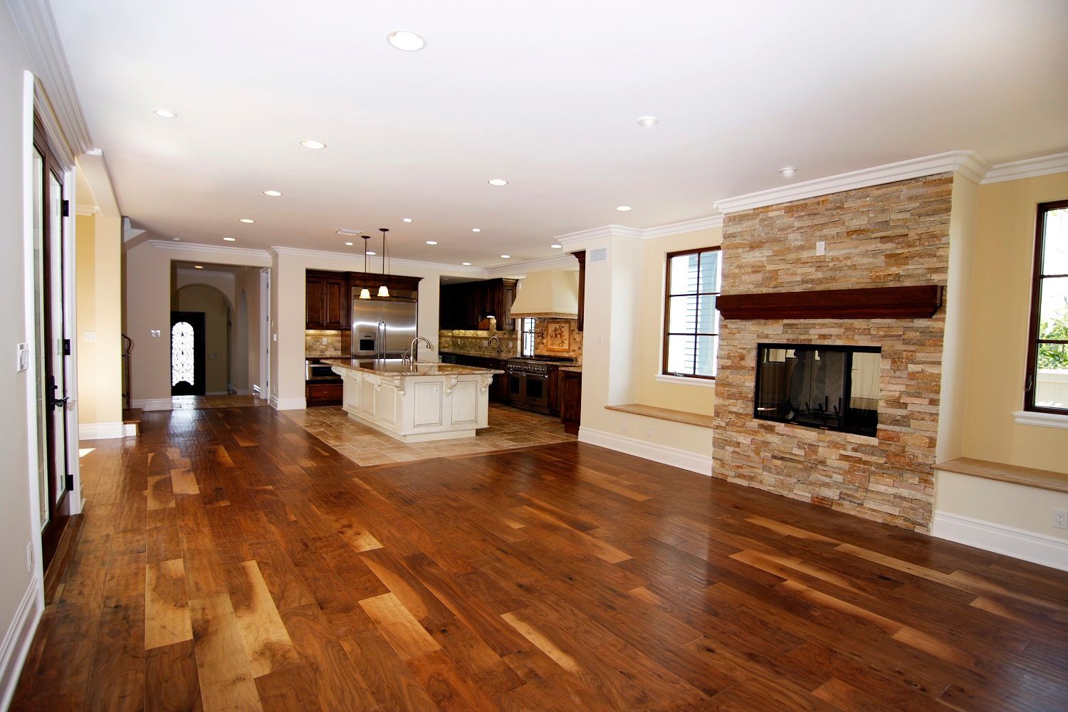 A large empty living room with hardwood floors and a fireplace. A large empty living room with hardwood floors and a fireplace.