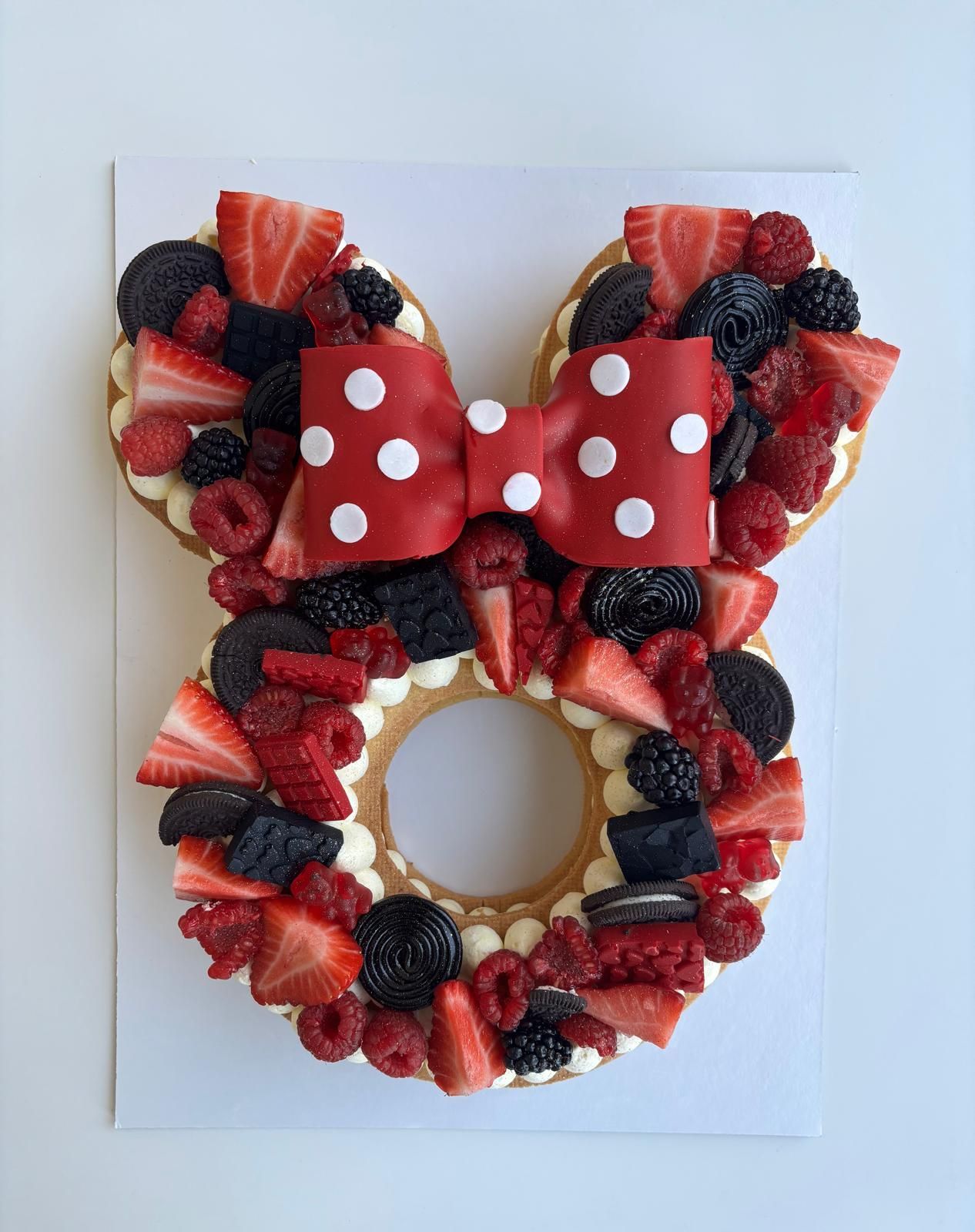 Dolce personalizzato a forma di Minnie con frutta, biscotti e fiocco rosso