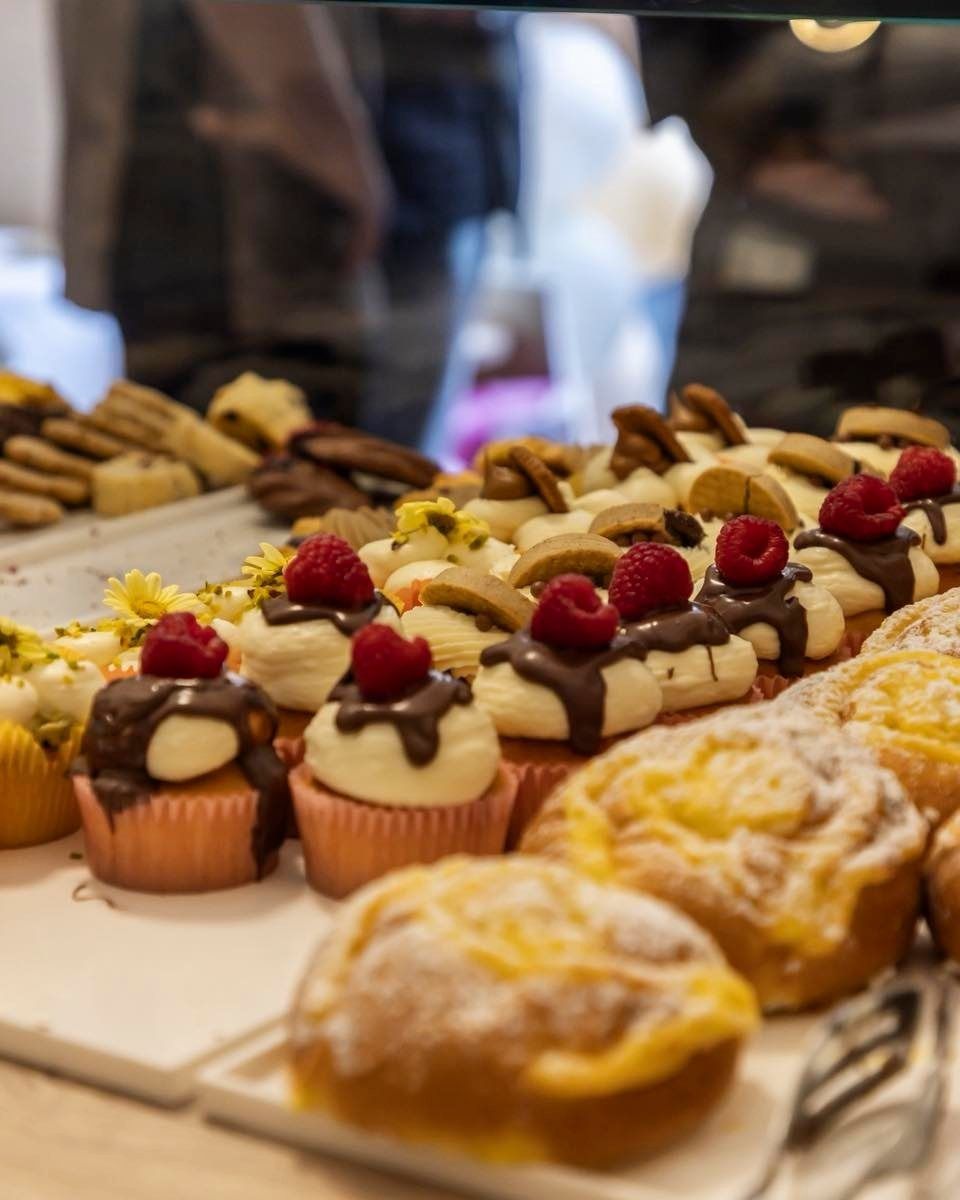 Vetrina di pasticceria in una panetteria, che espone torte e dessert colorati sotto luci intense.