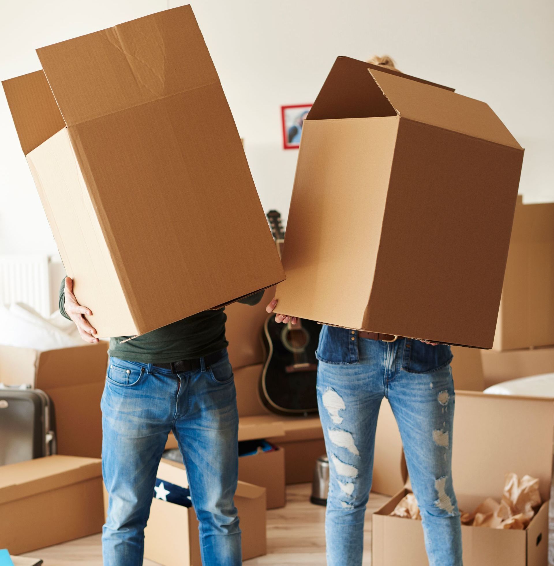 A man and a woman are holding cardboard boxes over their heads.