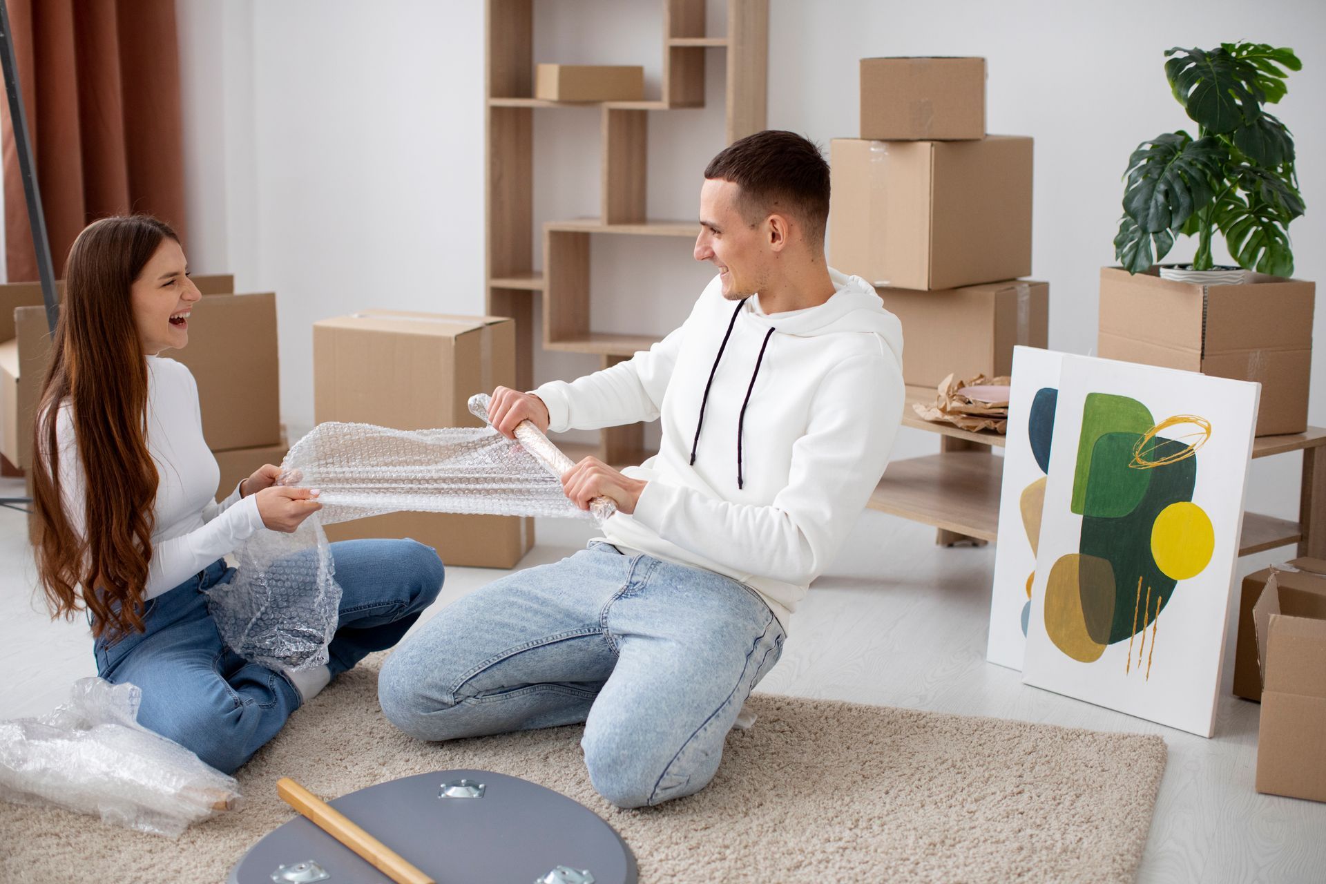 A man and a woman are sitting on the floor in a living room.