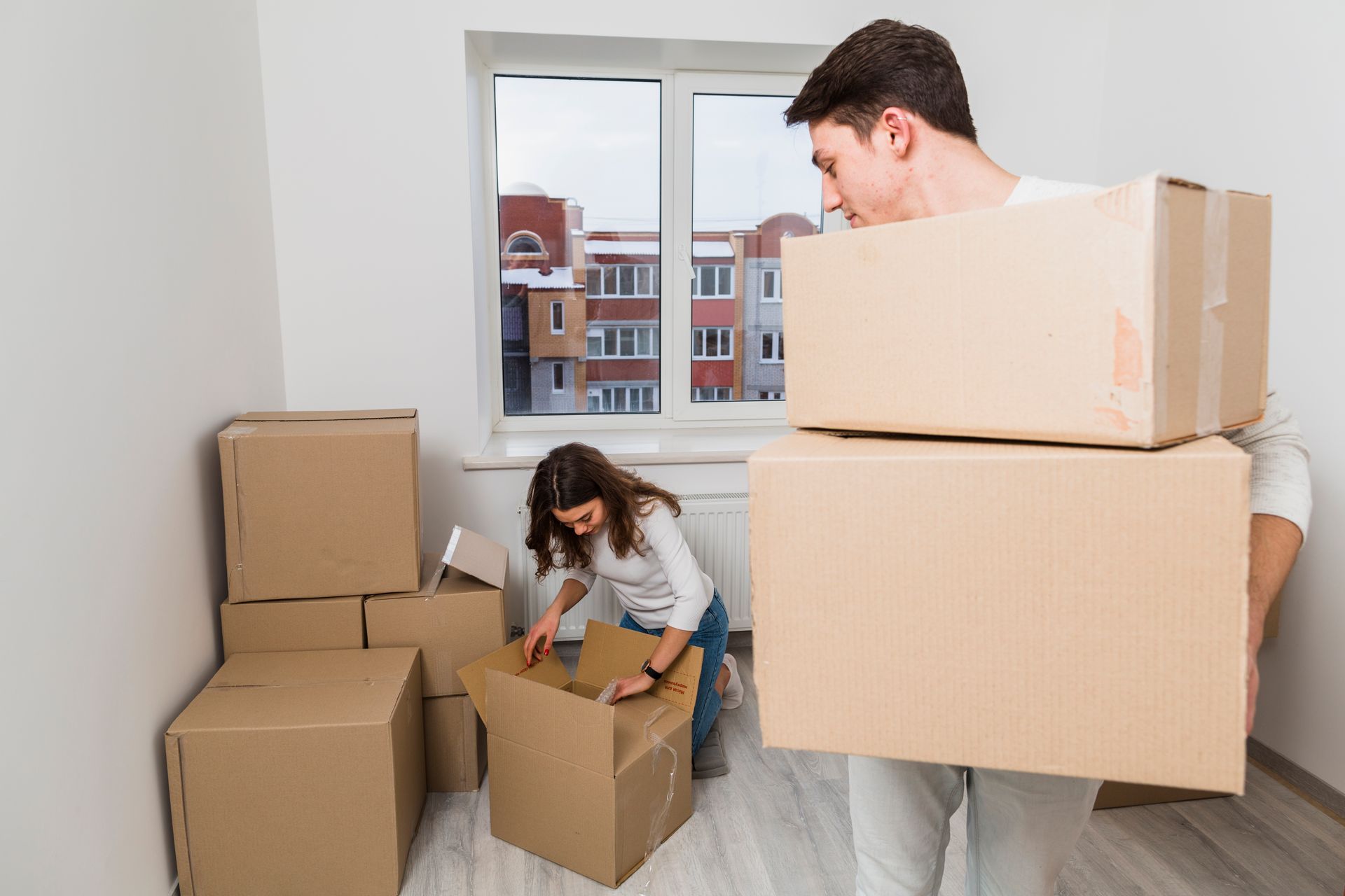 A man and a woman are packing boxes in an apartment.